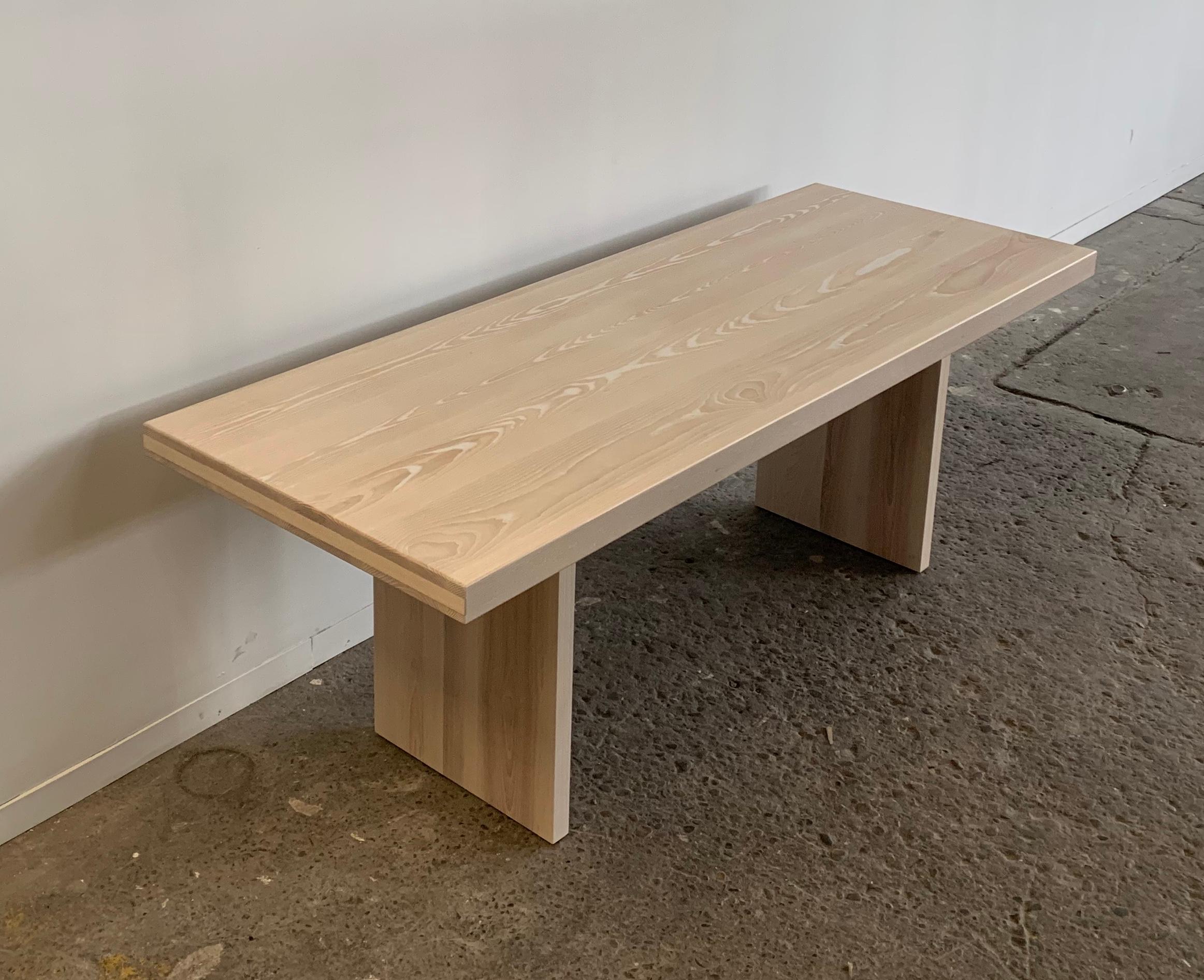 Handcrafted, bleached ash dining table. The sold table top rest upon two slabs of solid ash that are attached by hand cut white steel. The clean lines and right angles of this peace exude a minimalist style that if very appealing in any modern