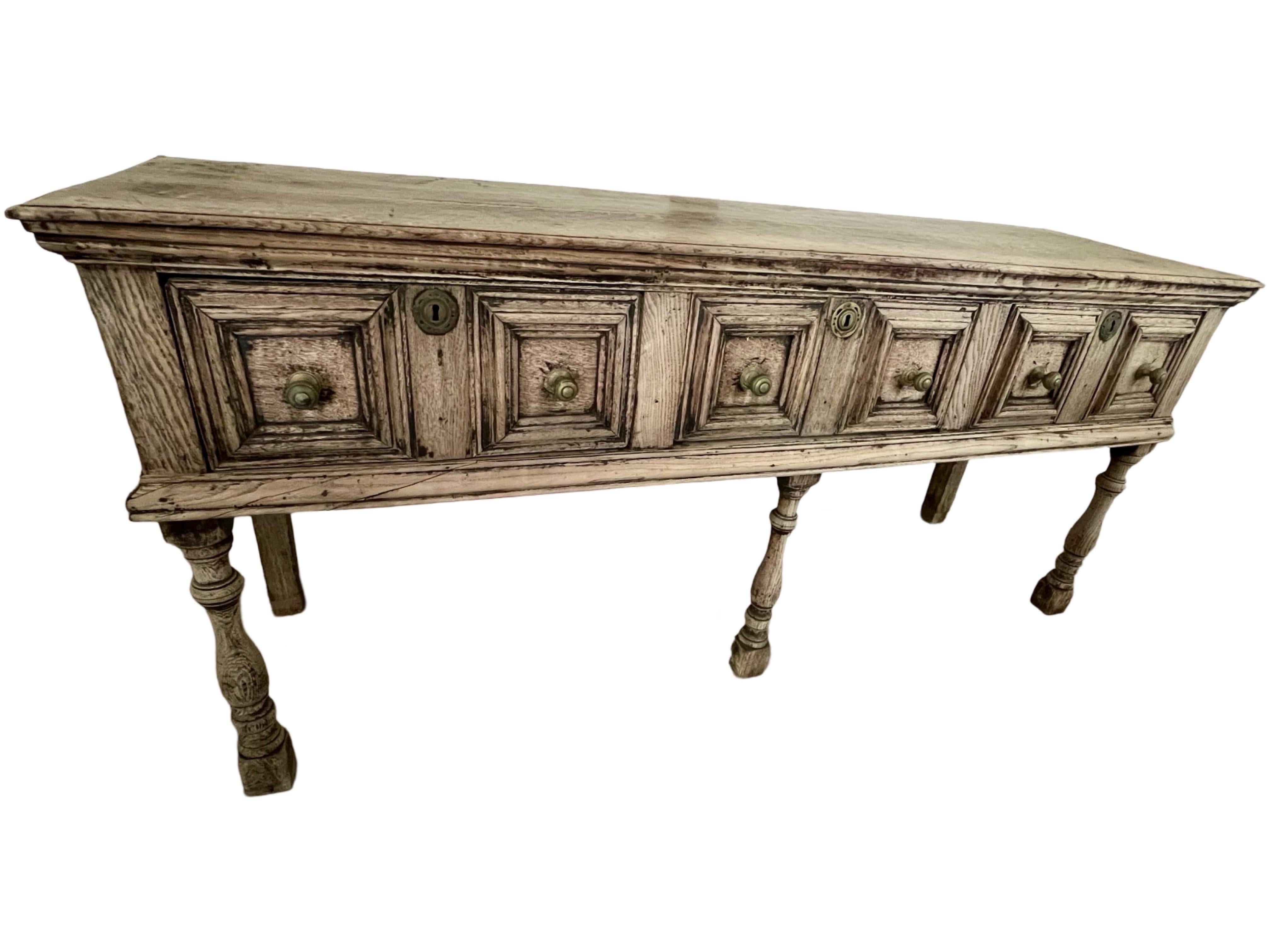 Period Jacobean dresser base / sideboard hand-crafted in England in the early 1800s (maybe even late 1700s) using oak and pegged construction. The dresser shows the typical molding decorations of the Jacobean style and features three inset drawers.