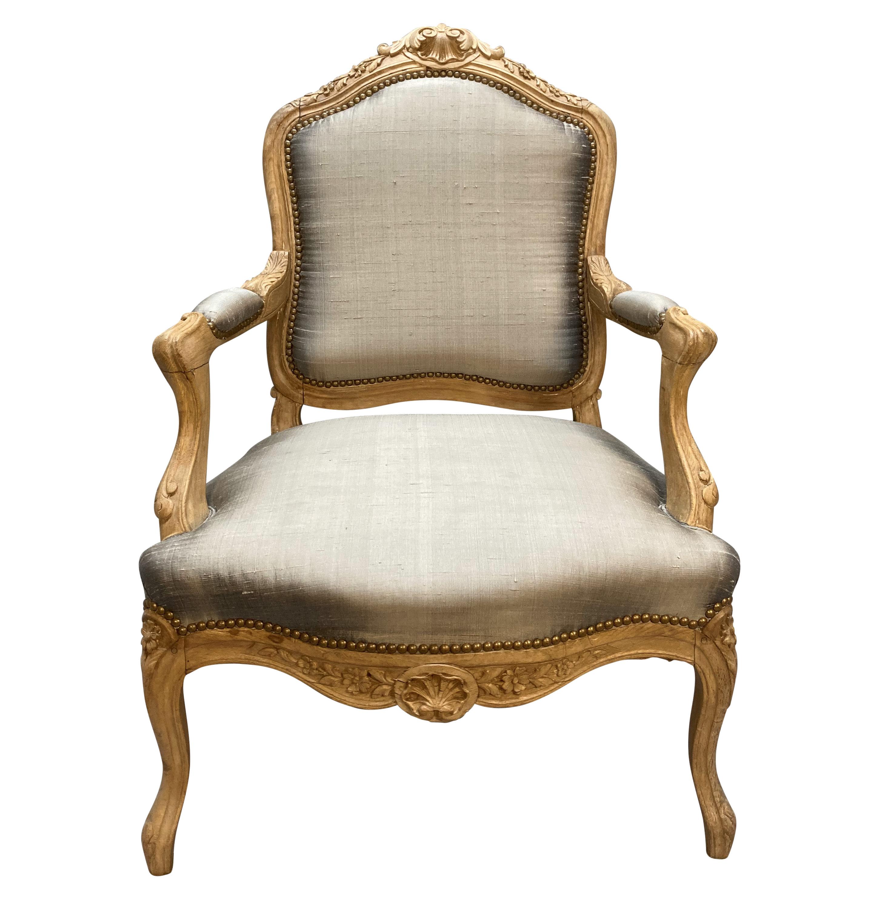 A French Louis XV armchair in bleached fruitwood. Beautifully carved with a good patina, newly upholstered in a stone coloured textured silk.