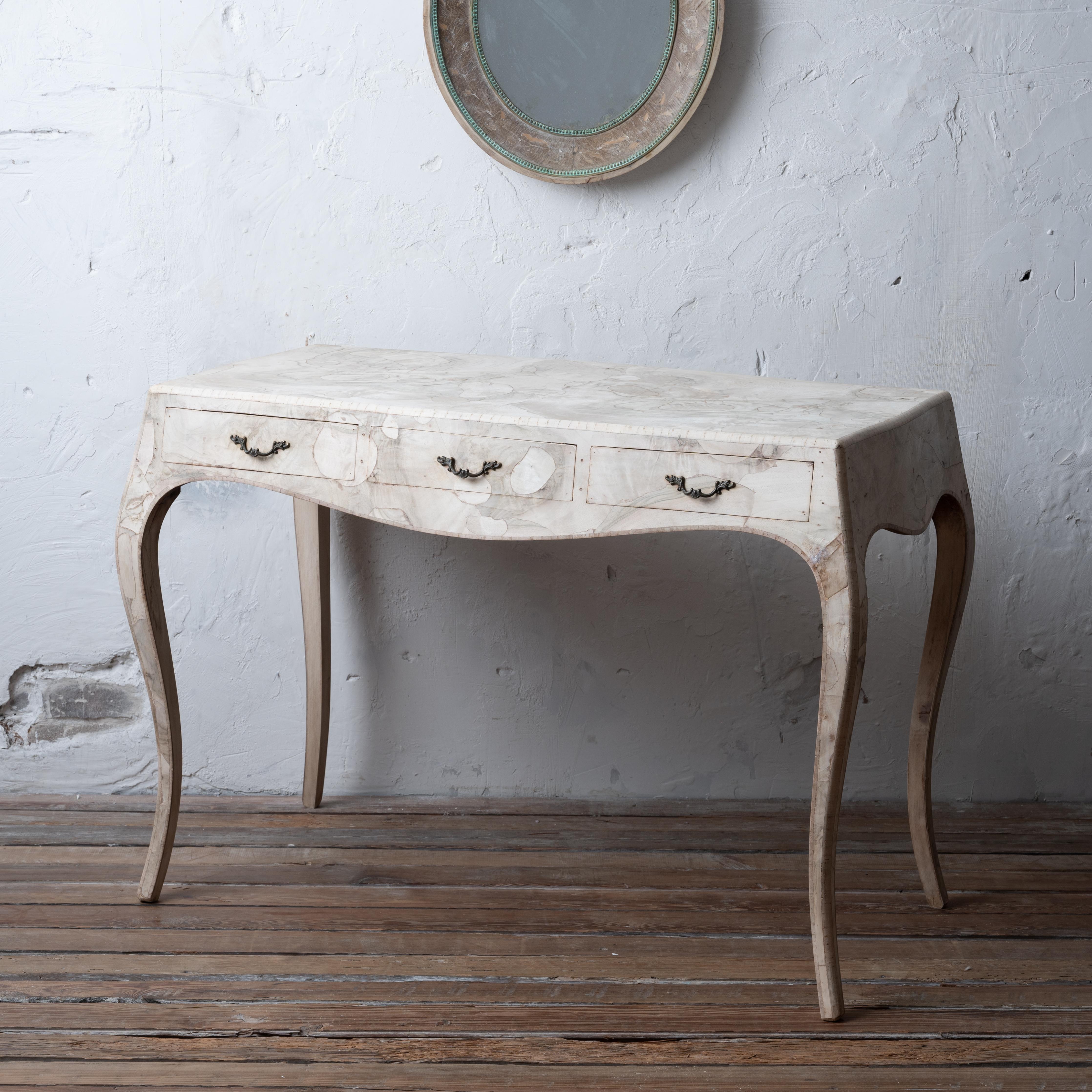 A bleached Italian patchwork veneer writing desk, circa 1950.

Three drawers that can face the wall for use as a console. 

42 inches wide by 21 ¾ inches deep by 29 ½ inches tall; knee clearance 22 ⅞ inches





