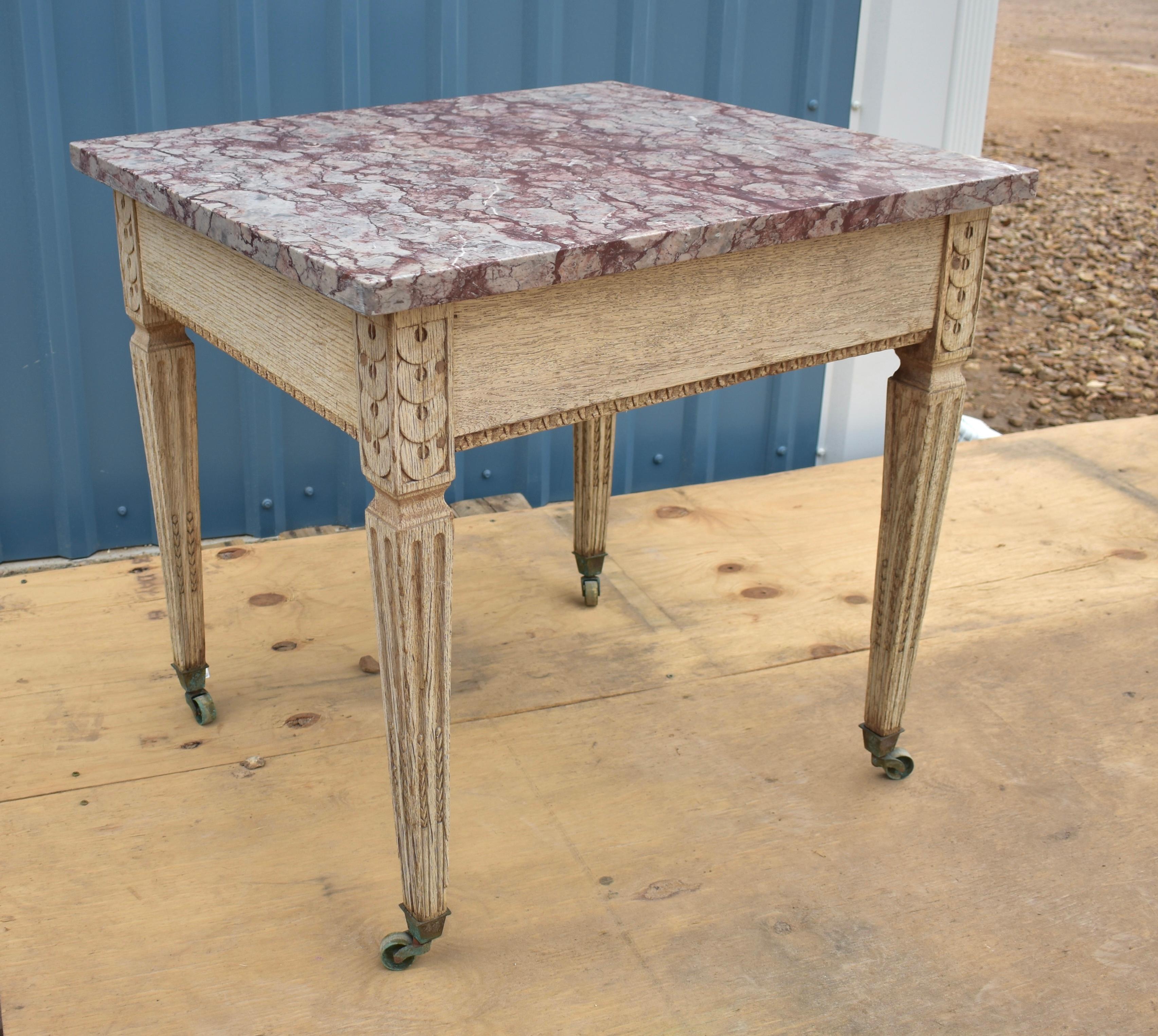 This is a beautifully hand-carved and hand-made Louis XVI side table built using oak in the late 1700s. Amazingly the table still sits on its original casters, however, the marble was replaced sometime in the mid 20th century. When looking at this