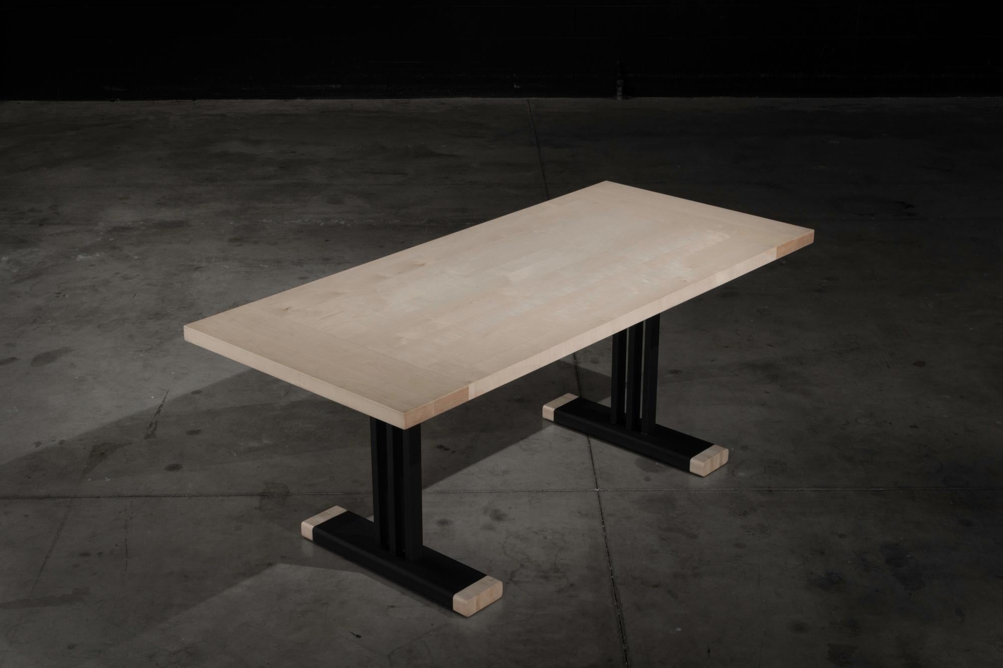 Made of a bleached hard maple top and a wrinkle black powder-coated base, the Trumbull dining table fits many modern spaces with its sleek design. Made of solid maple, the top of this table also encompasses a breadboard design to add style to the