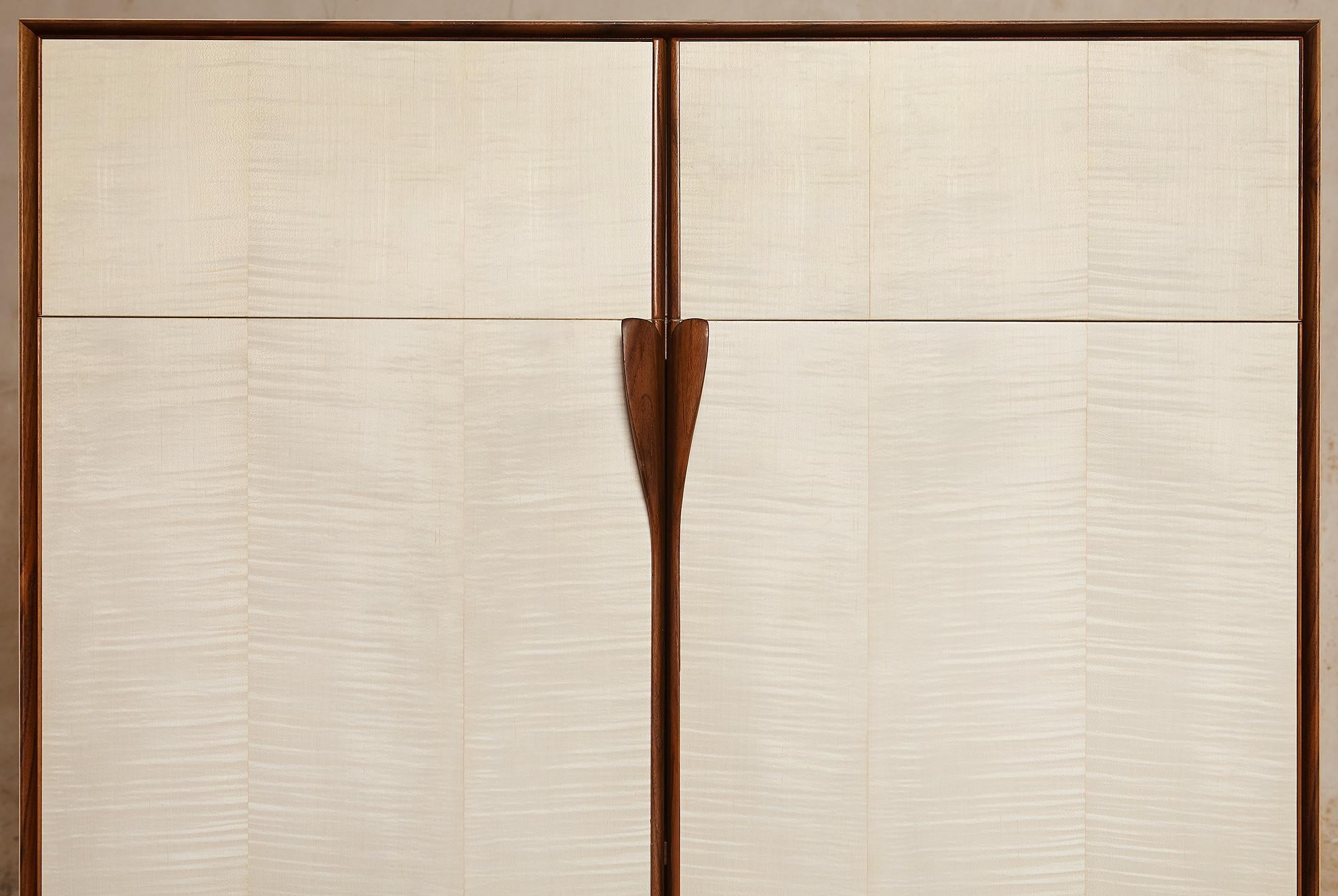 Tall and well-proportioned cabinet unit in bleached maple veneer with walnut solid wood framing.
The quarter inch thick walnut profile frames the piece and divides the different units, and transforms into legs at the base and into the shaped leaves