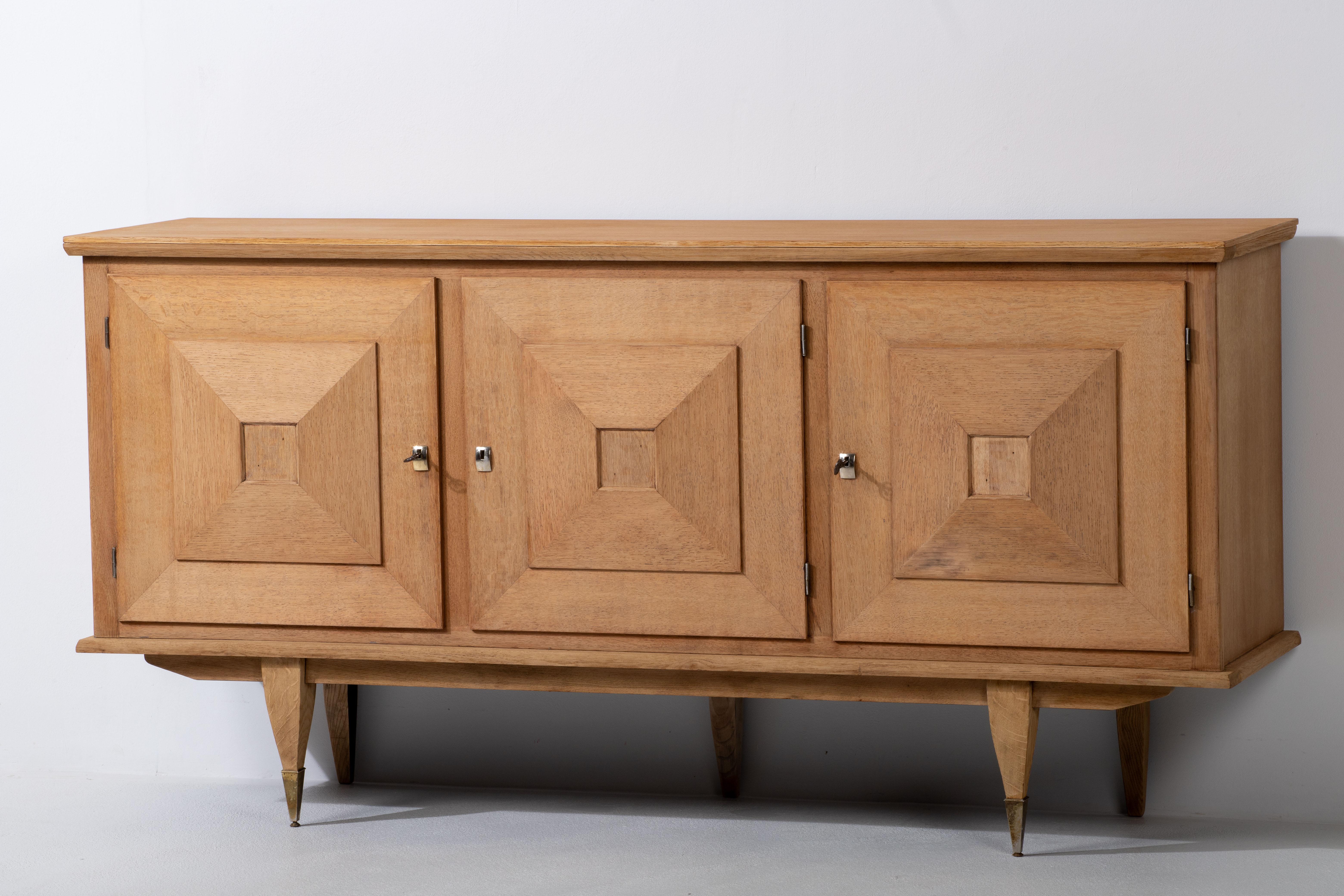 Presenting a credenza from the 1940s, meticulously crafted in France from solid oak. This Art Deco Brutalist sideboard exudes a captivating charm that seamlessly blends form and function. Comprising four spacious storage compartments, the credenza