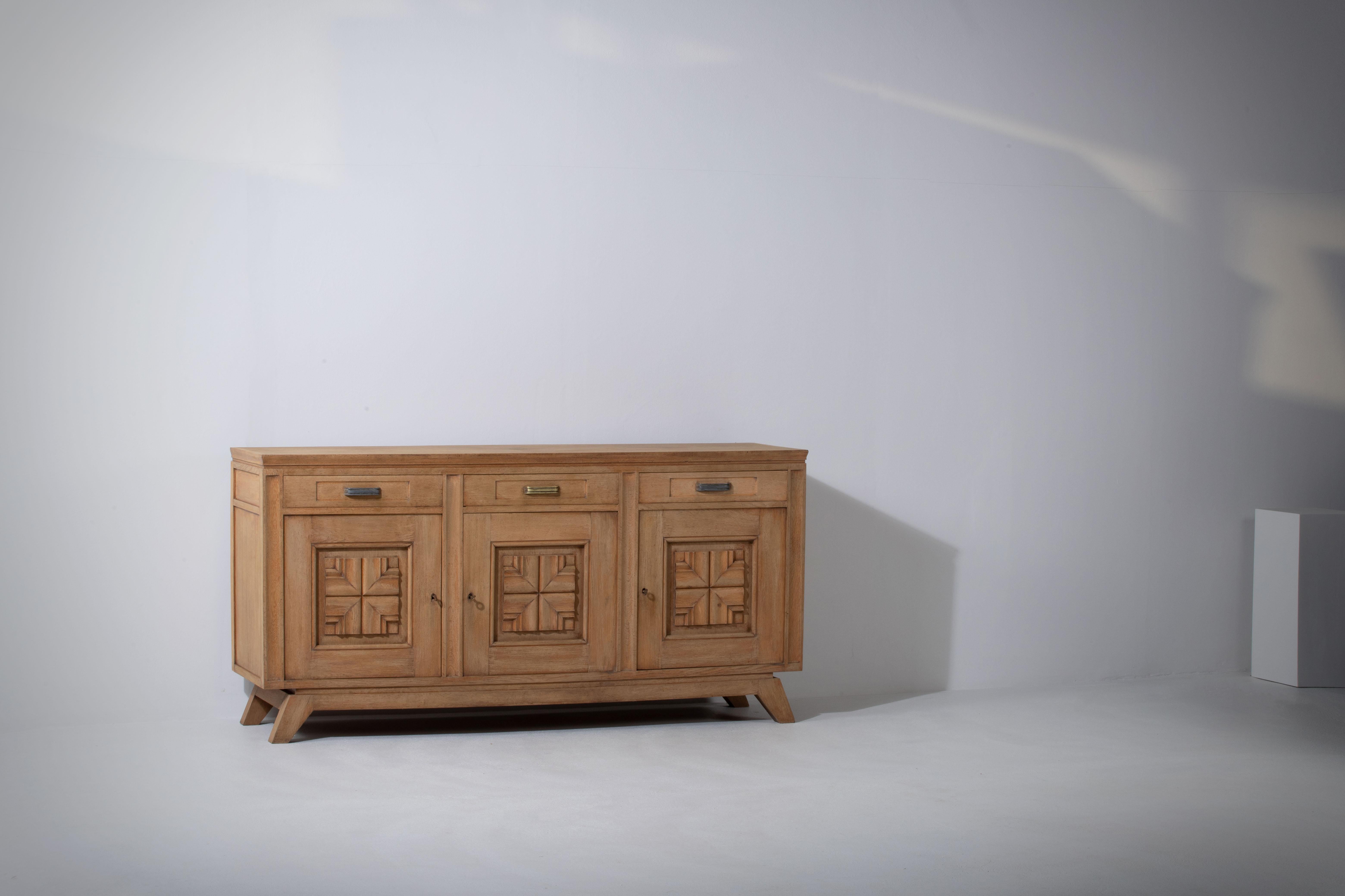 Credenza, solid oak, France, 1940s.
Art Deco brutalist sideboard. 
The credenza consists of three storage facilities and covered with very detailed designed doors and at the top, a drawers line.
 