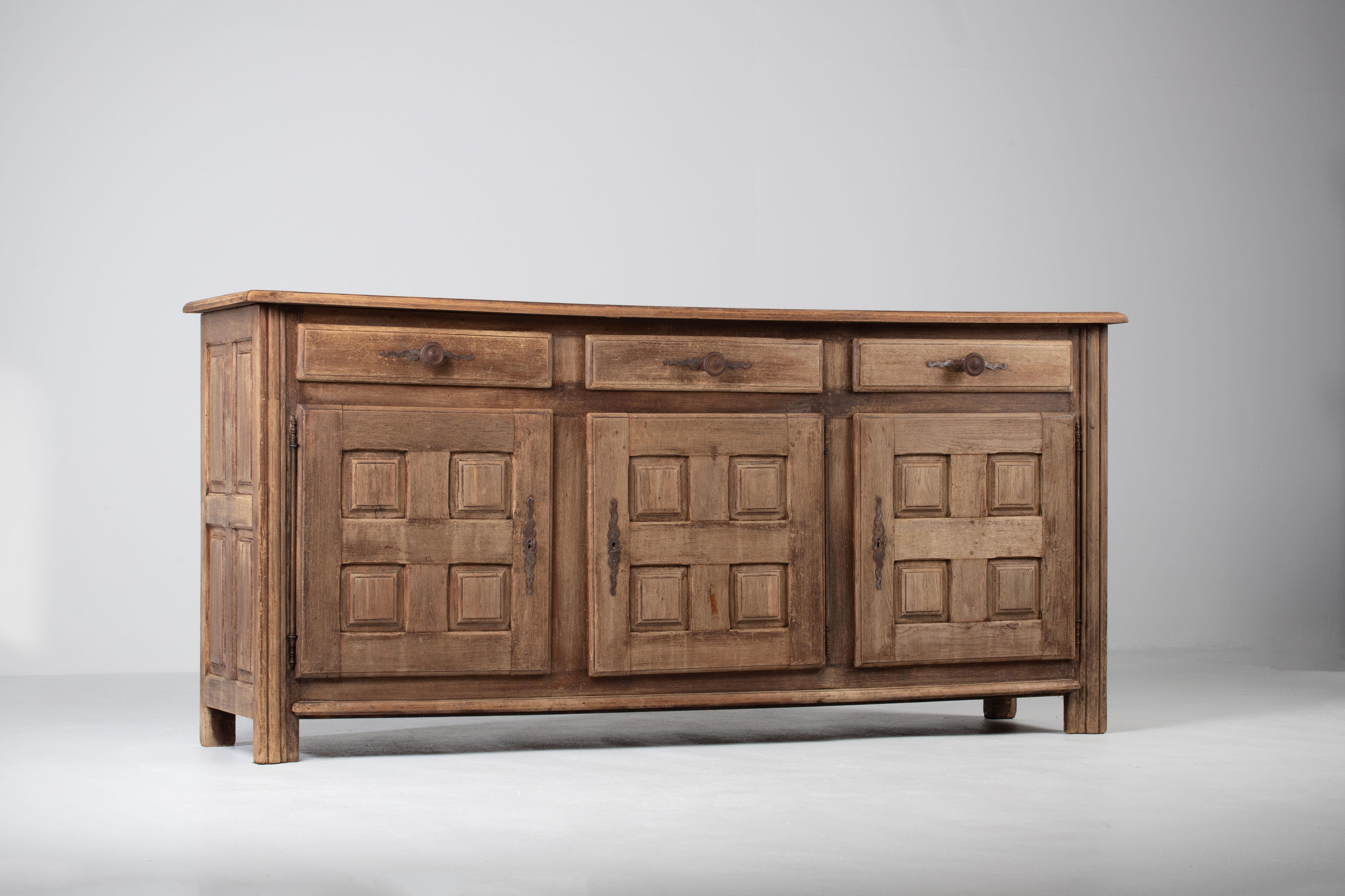Bleached solid oak credenza, France, 1940s.
Large mid-century Brutalist sideboard. 
The credenza consists of three central storage facilities and covered with very detailed designed doors. 


