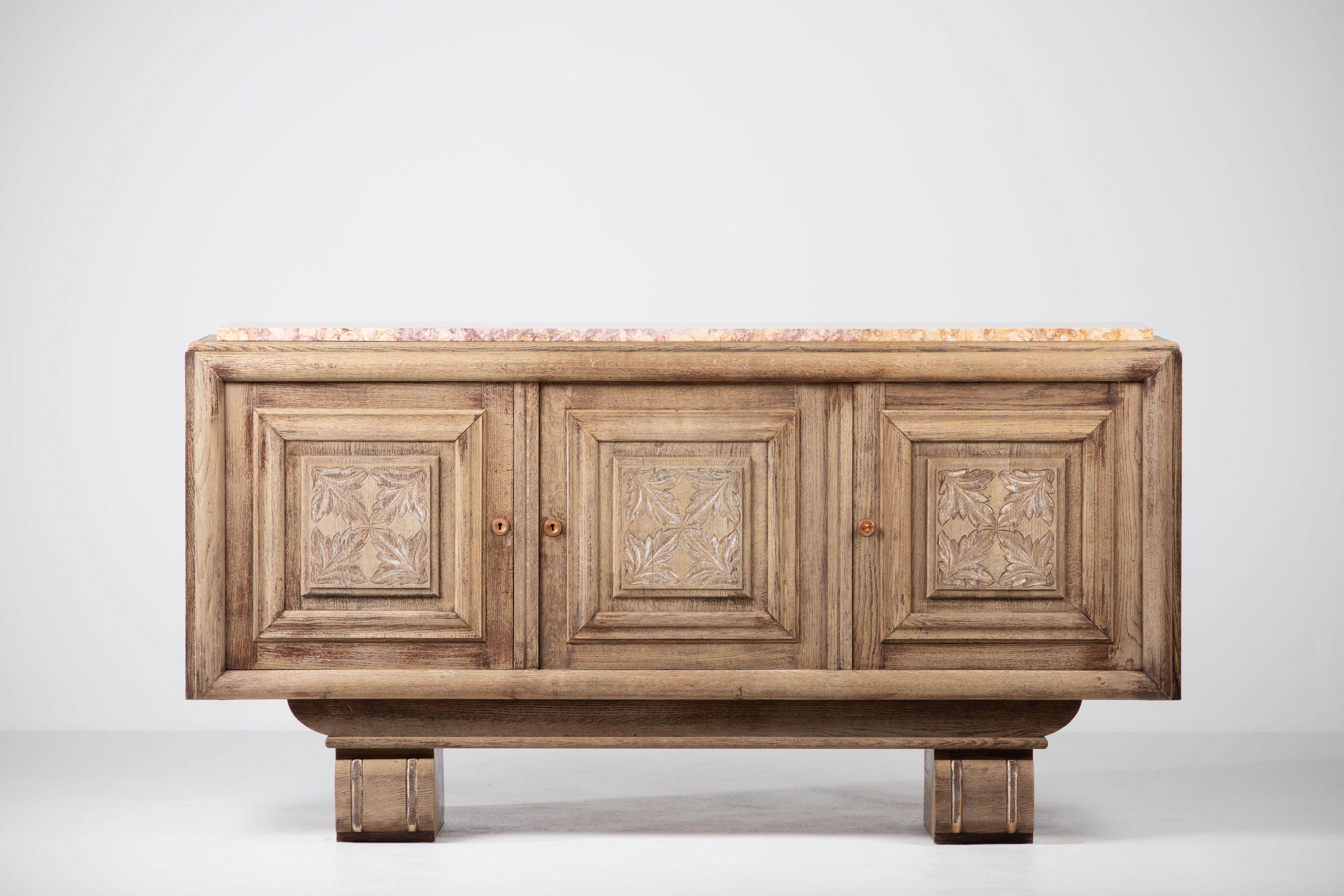 Bleached solid oak credenza, France, 1940s.
Large mid-century Brutalist sideboard. 
The credenza consists of three central storage facilities and covered with handcarved leaves design doors. 

