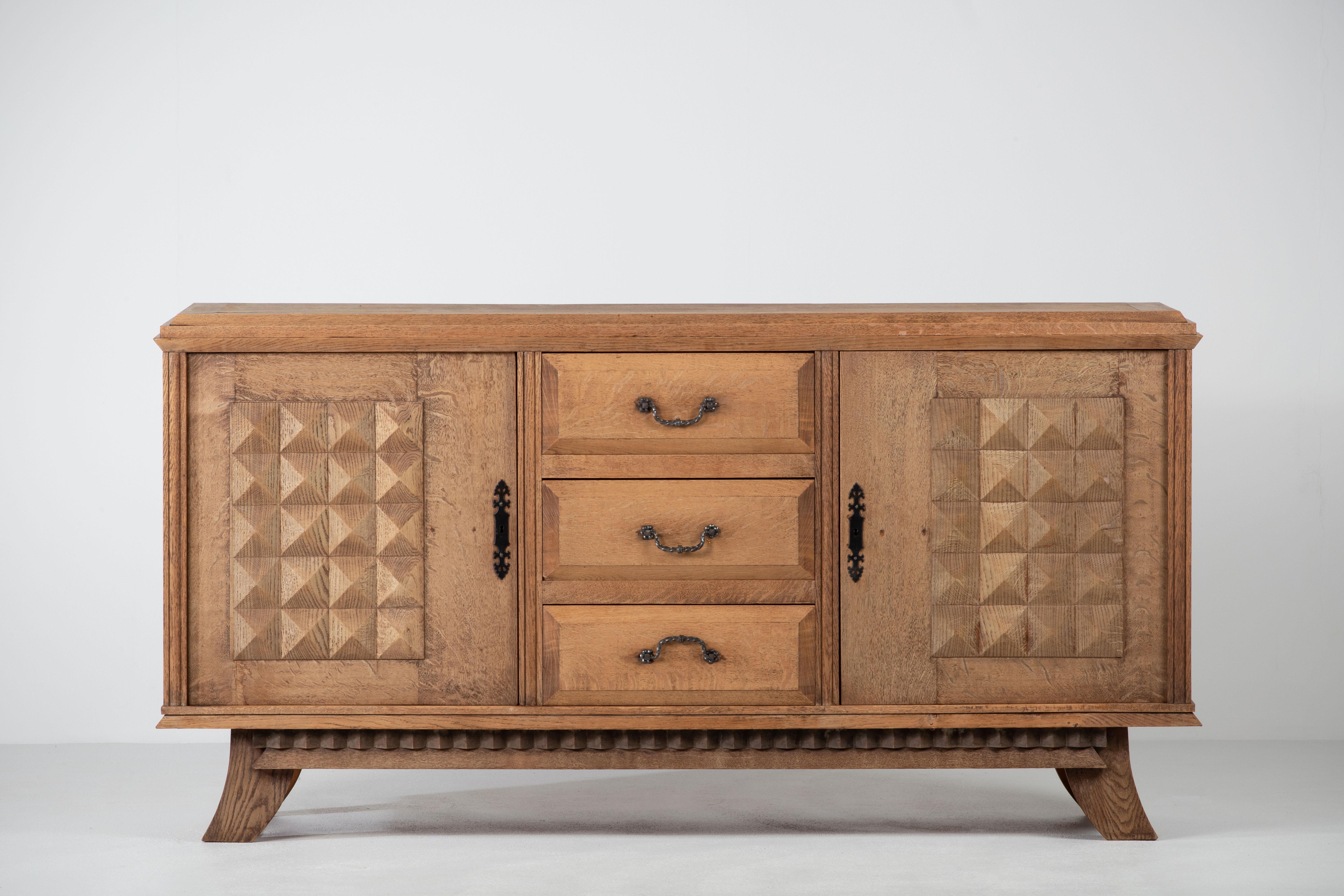 Large Credenza, solid oak, France, reminiscent of the work of Charles Dudouyt, 1940s.
Large Art Deco Brutalist sideboard. 
The credenza consists of two storage facilities and covered with very detailed designed doors, in the center, drawers.
The