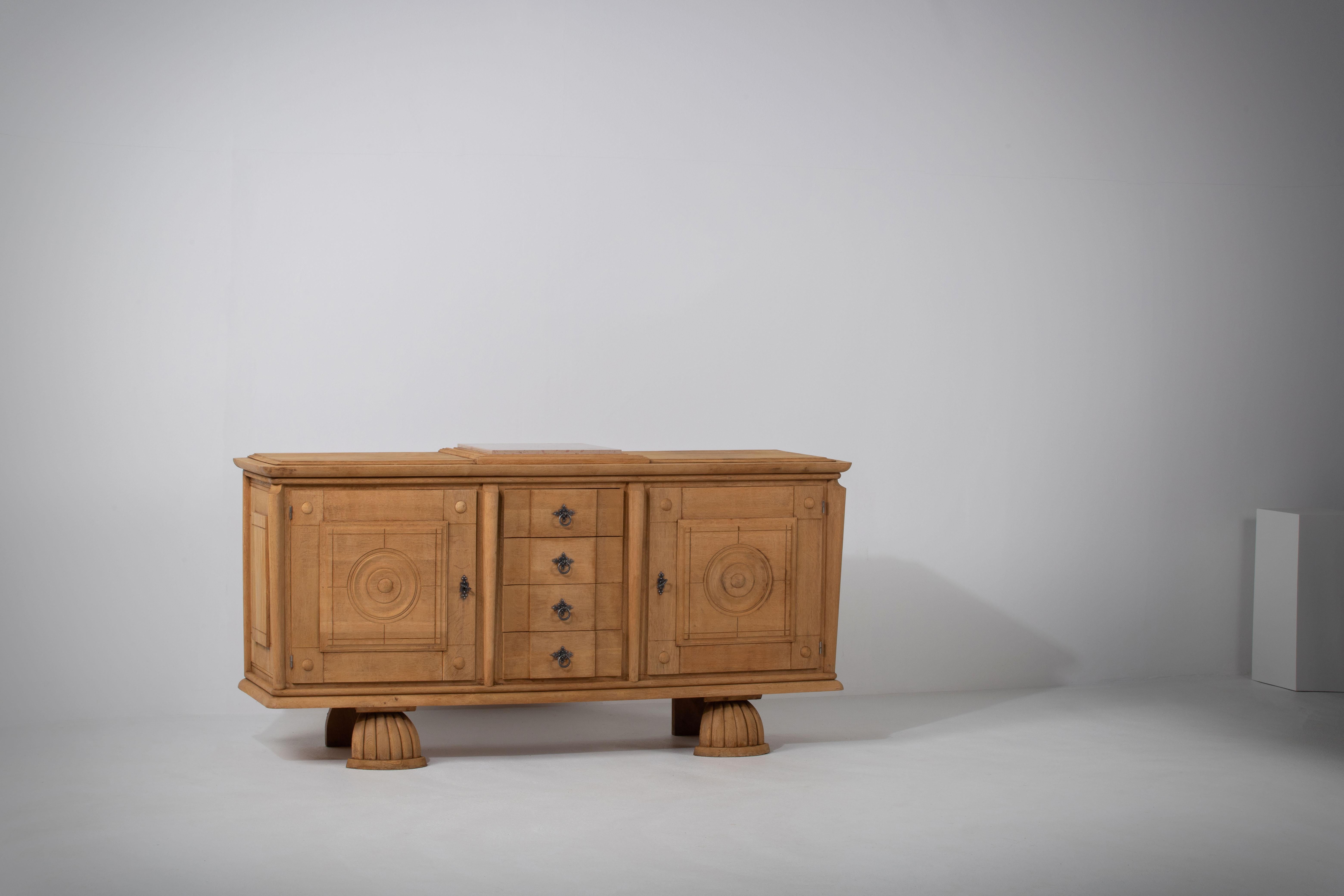 Credenza, solid oak, France, 1940s.
A matching sideboard is available.
Large Art Deco brutalist sideboard. 
The credenza consists of two storage facilities with the center drawers. 
The refined wooden structures on the doors create a striking