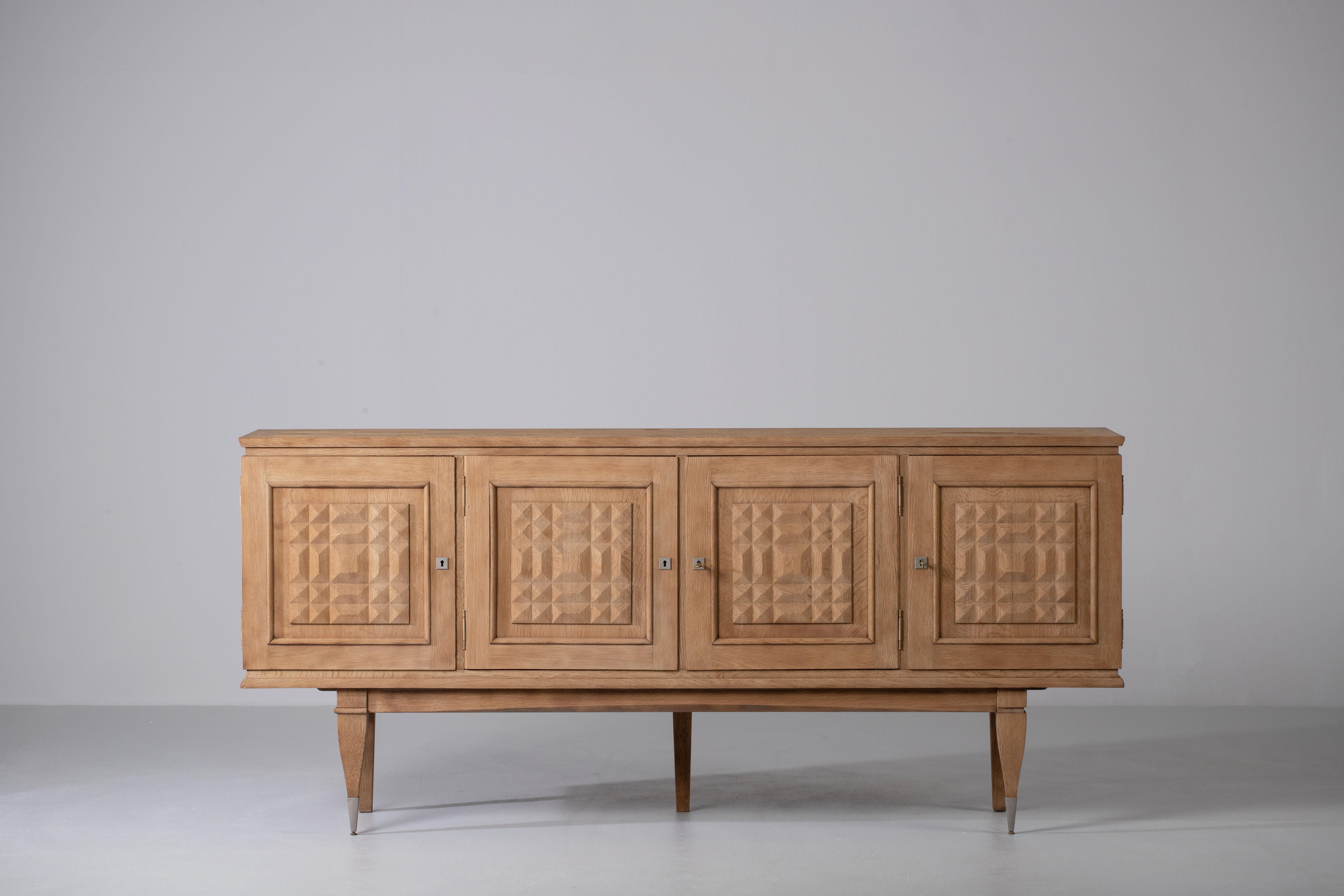 Credenza, solid oak, France, 1940s.
Large Art Deco Brutalist sideboard. 
The credenza consists of two central drawers and three storage facilities and covered with very detailed designed doors. 
The refined wooden structures on the doors create a