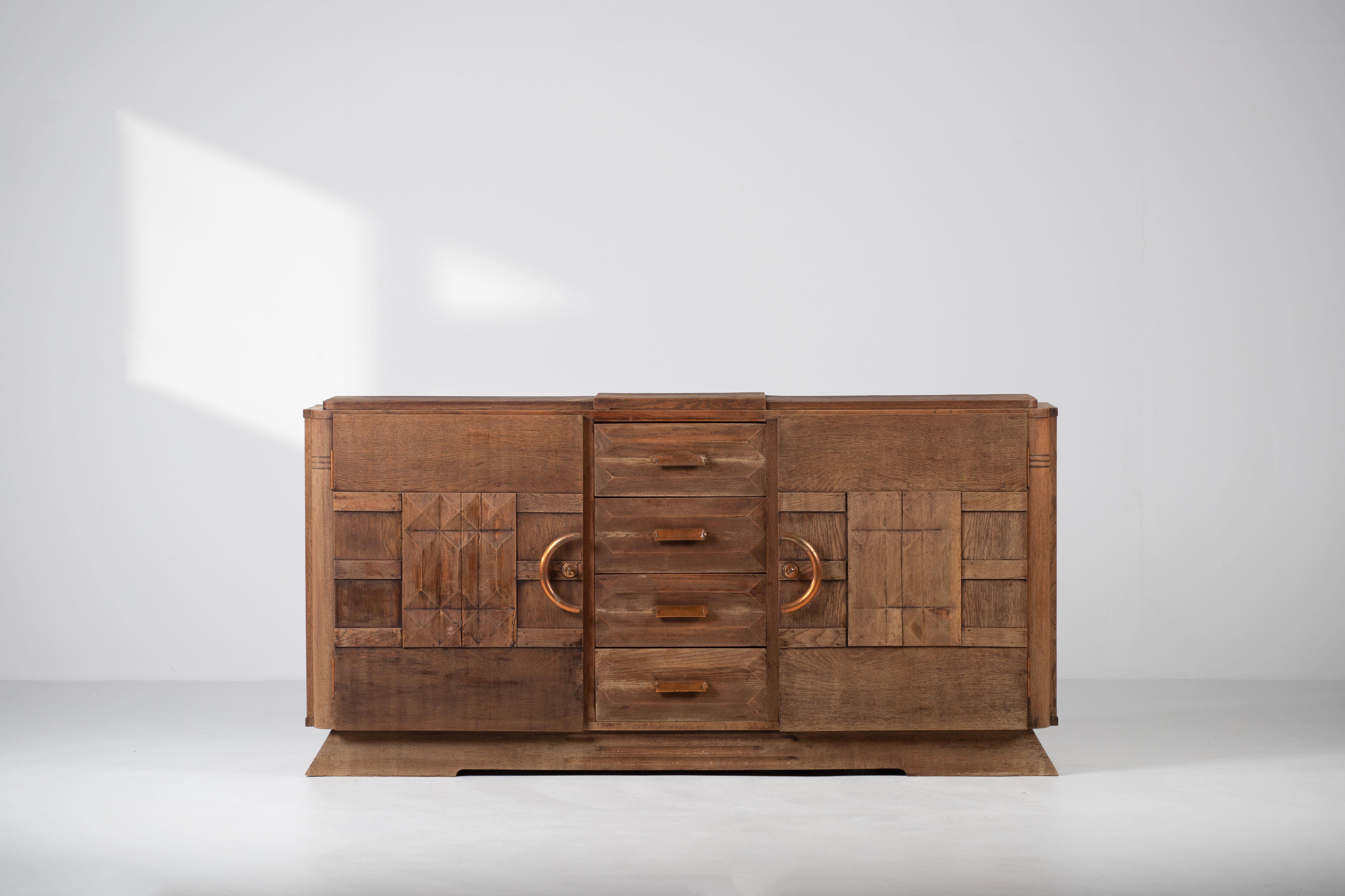 Credenza, solid oak, France, 1940s.
Large Art Deco Brutalist sideboard. 
The credenza consists of four central drawers and two storage facilities and covered with very detailed designed doors. 
The refined wooden structures on the doors create a