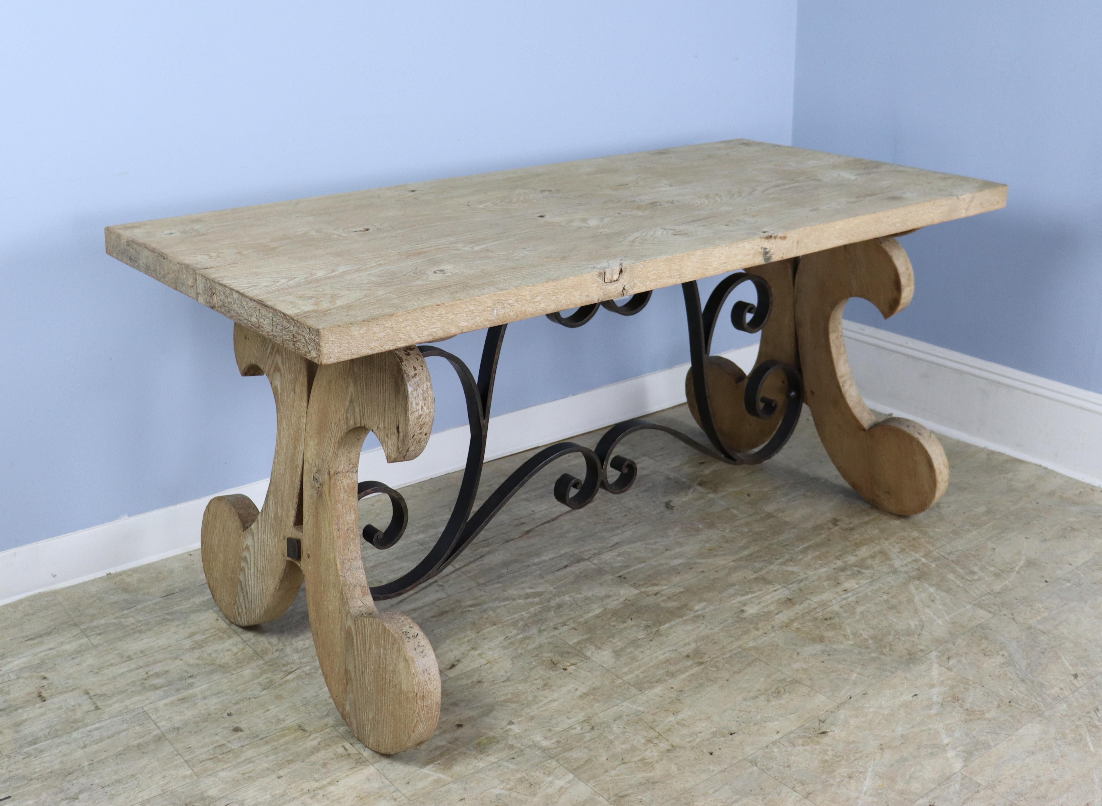 A handsome bleached oak farm table with an Iberian style trestle base and a 2 inch thick top. The piece has very good oak grain throughout and the light wood gives it a modern sensibility. No apron or legs means this table can accommodate 6, and