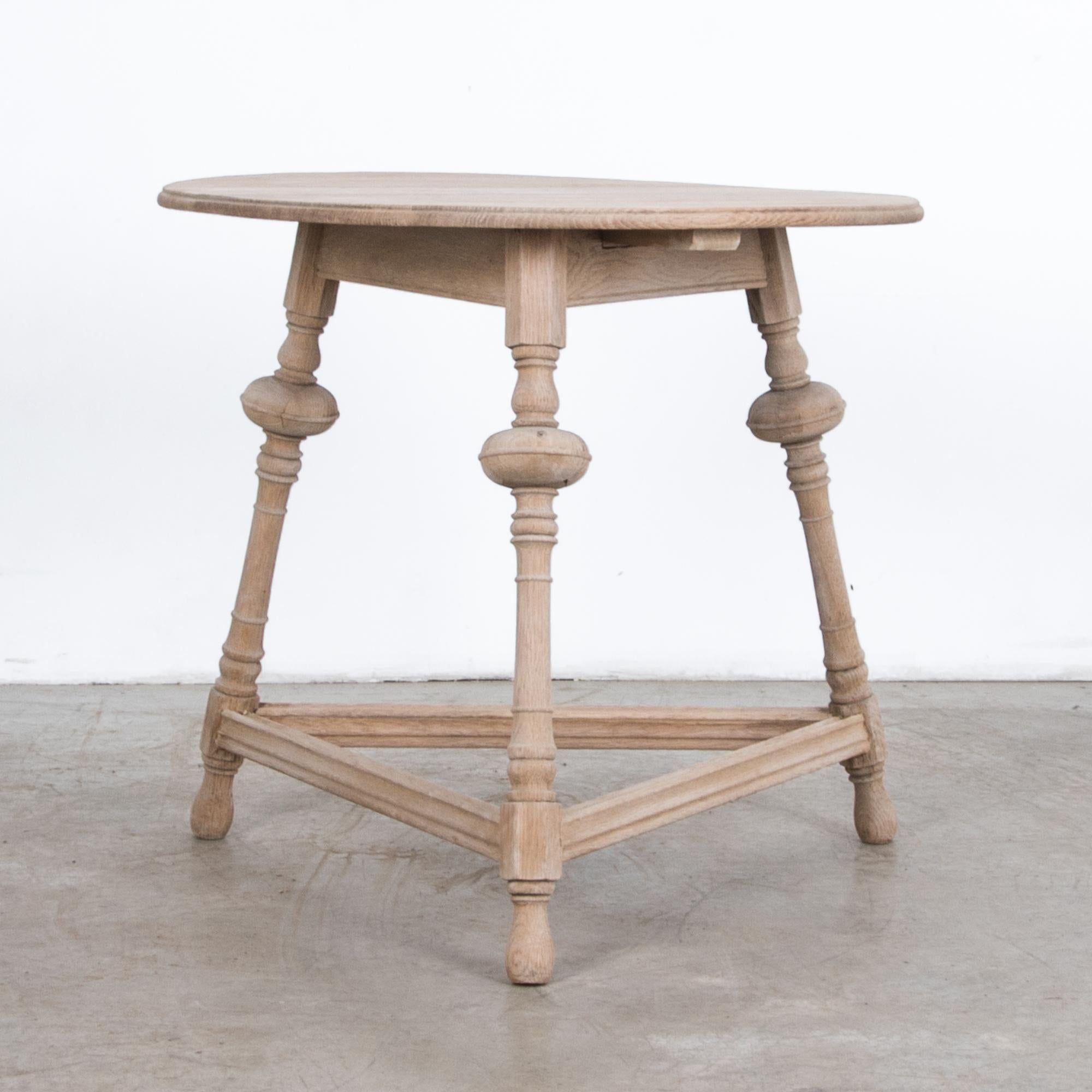 From the United Kingdom circa 1920, an oak side table with circular top. Carved in oak, this Provincial table is simple and elegant, with distinctive turned legs arranged in triangle configuration.