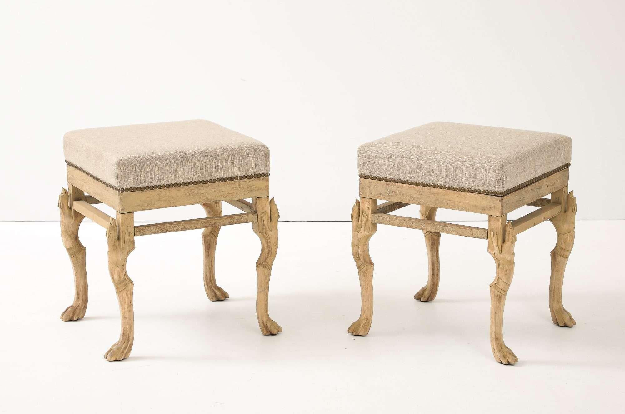 Pair of square hoofed-foot stools in bleached wood, newly upholstered in neutral linen with brass nail-head trim—perfect as extra seating or chic bedside perches. Sold individually.