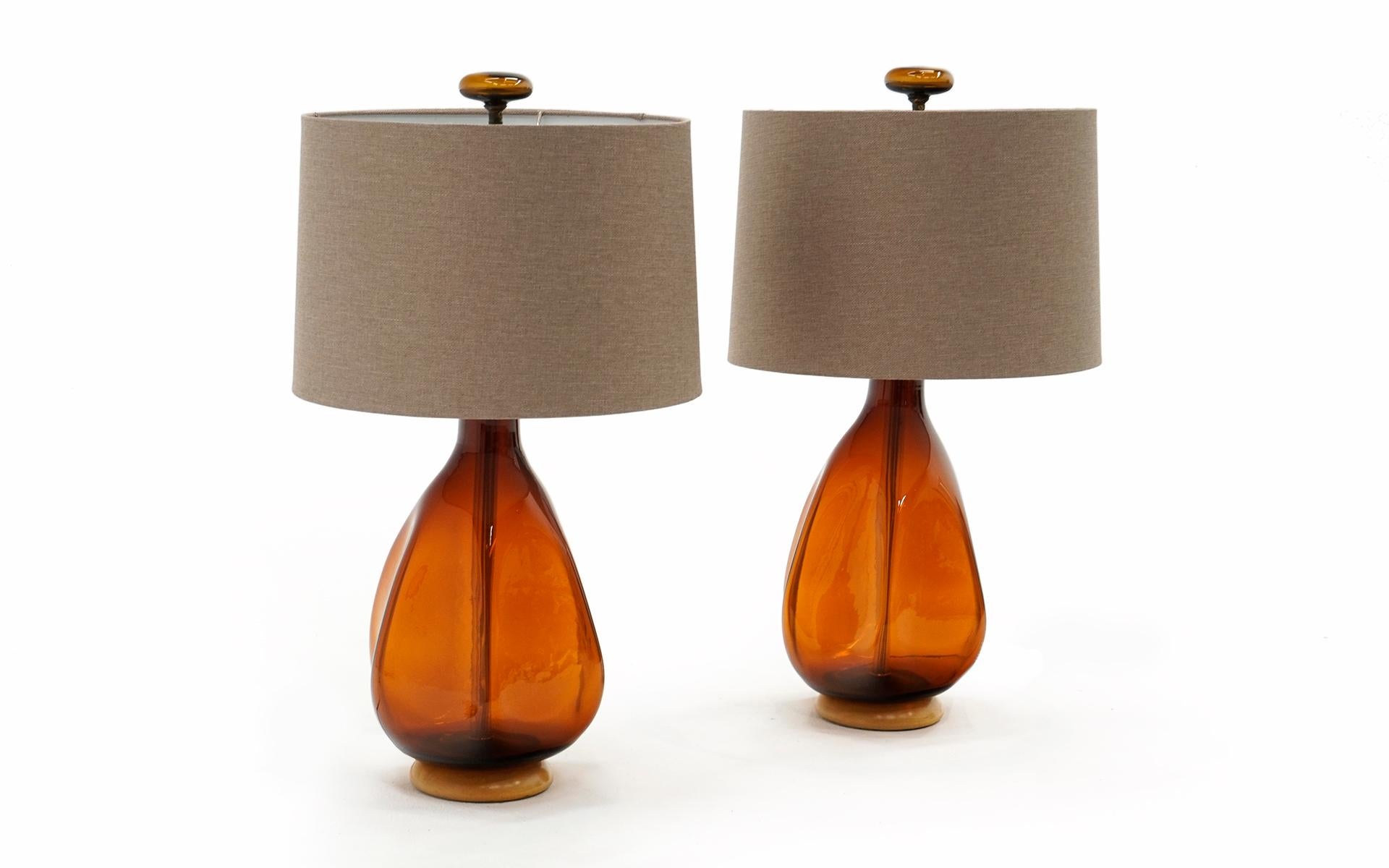 Pair of Art Glass Table Lamps by Blenko American Art Glass, 1950s. Burnt orange / Amber blown glass with blonde wood base and brass harp and fixture. Complete the the original blown glass finials. No Chips, cracks or repairs. Both working and ready