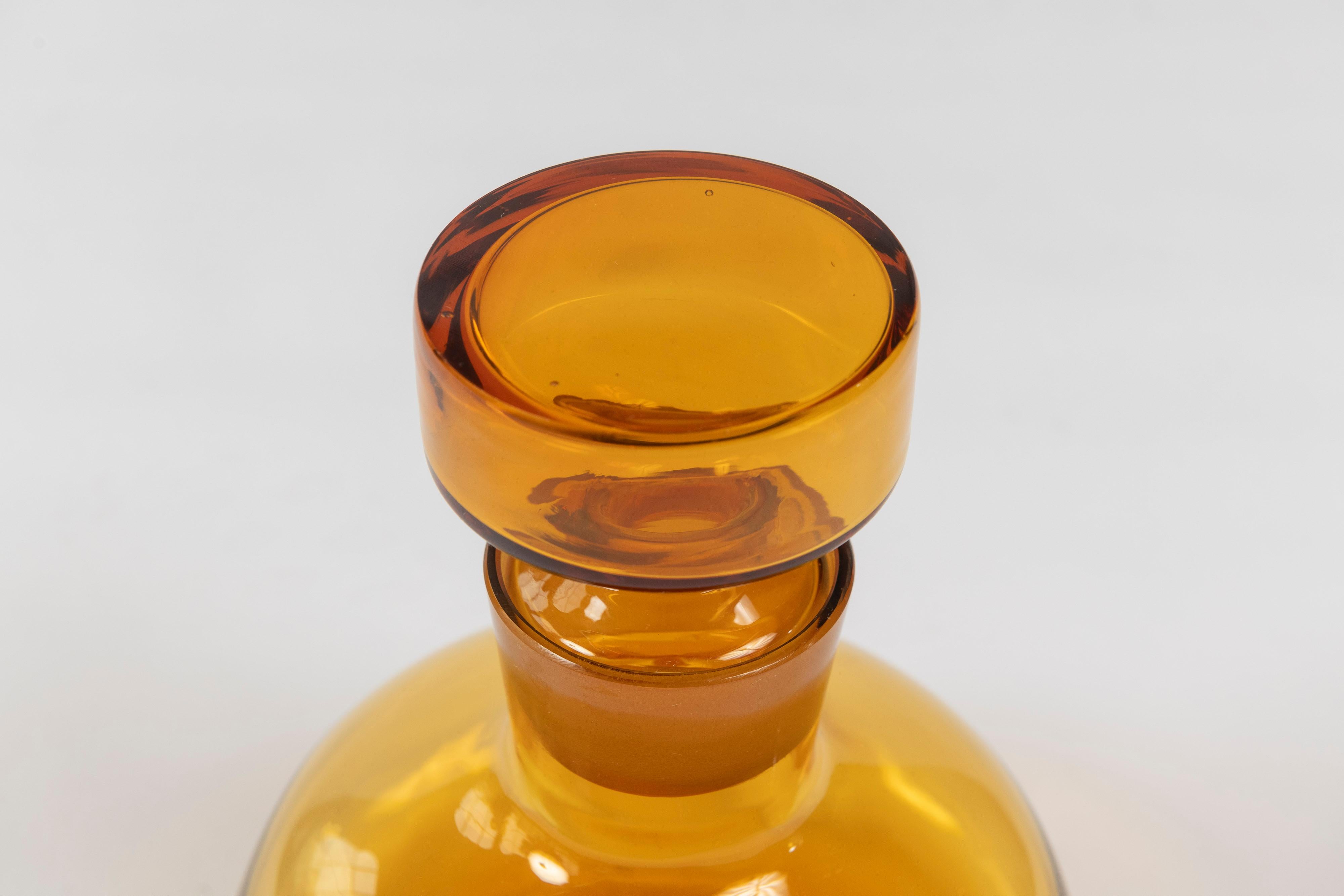 Exquisite amber hued Mid-Century Modern decantor with stopper is attributed to Blenko Glass Company. This vintage piece is in excellent condition and a wonderful addition to any bar or glass collection.
