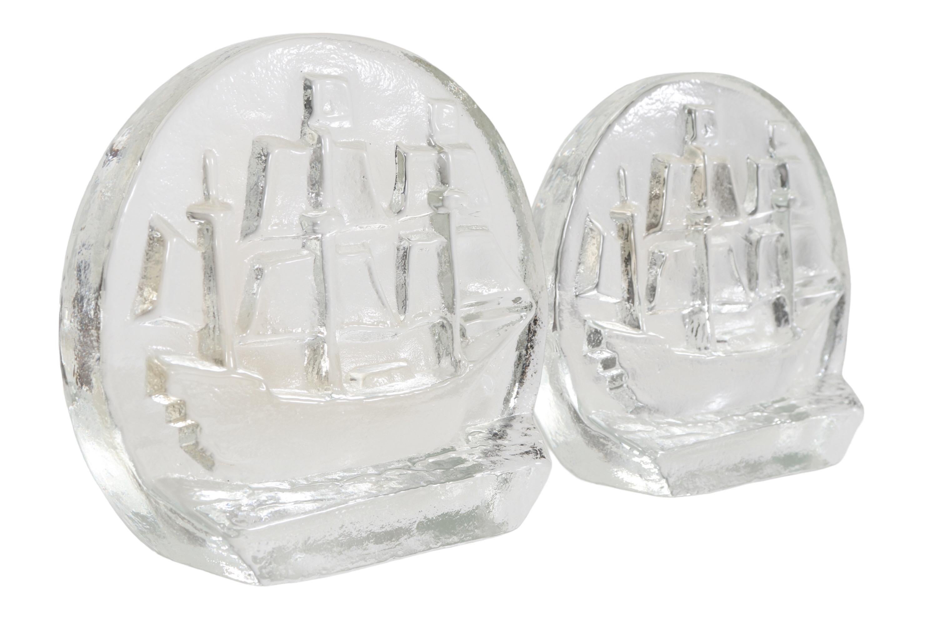 A pair of round art glass bookends made by Blenko. Decorated with ships at full sail above a stretch of water in textured relief. Dimensions per bookend