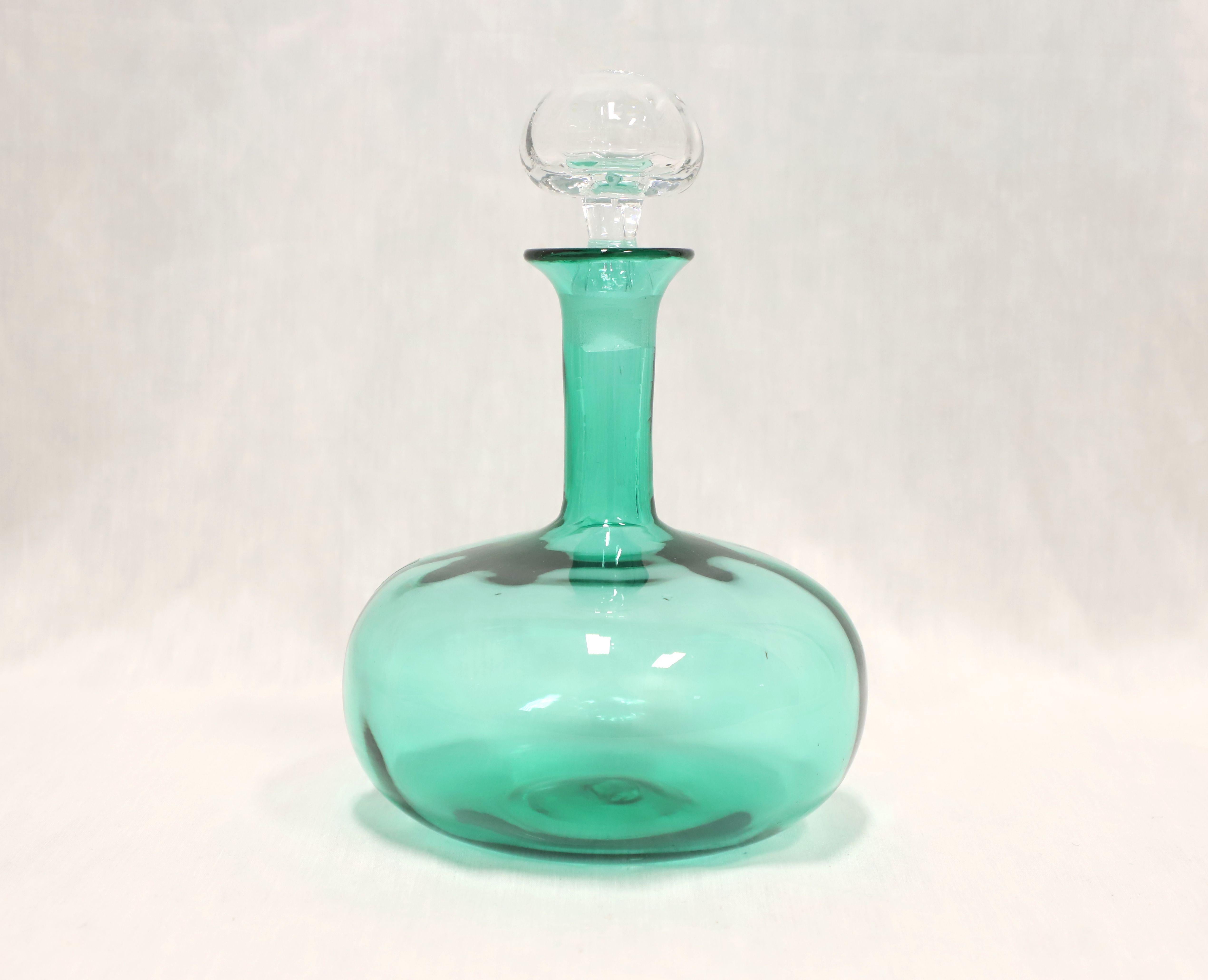 A Mid 20th Century hand-blown glass decanter by Blenko Glass. Green glass decanter with squat round shape and a long neck. Clear round shaped glass stopper. Handmade in Milton, West Virginia, USA.

Measures:  7w 7d 10h, Weighs Approximately:  3