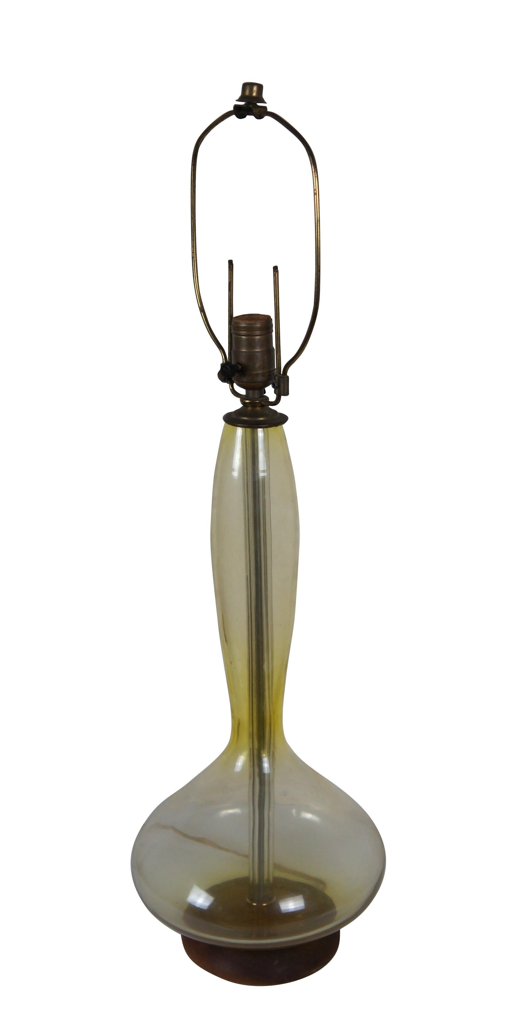 Mid 20th century Blenko glass genie bottle Jonquil table lamp in Lemon (pale yellow) with round walnut base. Style number 5815 (as seen in Blenko's 1958 catalog) designed by Wayne Husted. Attached, adjustable height harp and cap shaped finial -