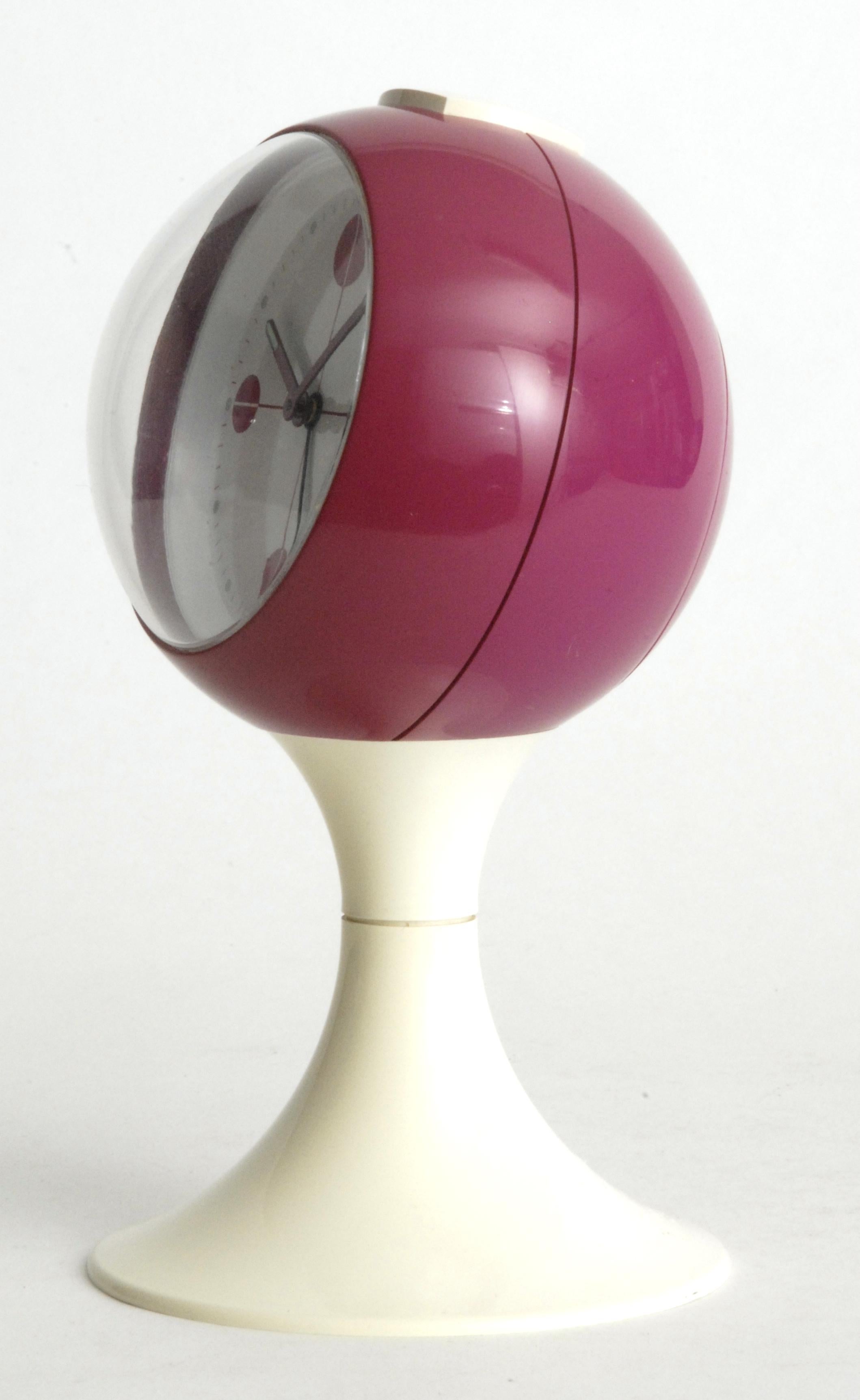 A pedestal clock design in the form of a ball in maroon and white. An alarm clock with separate spring mechanisms for the time and alarm winding. it comes complete with its back cover, these are usually lost over time.