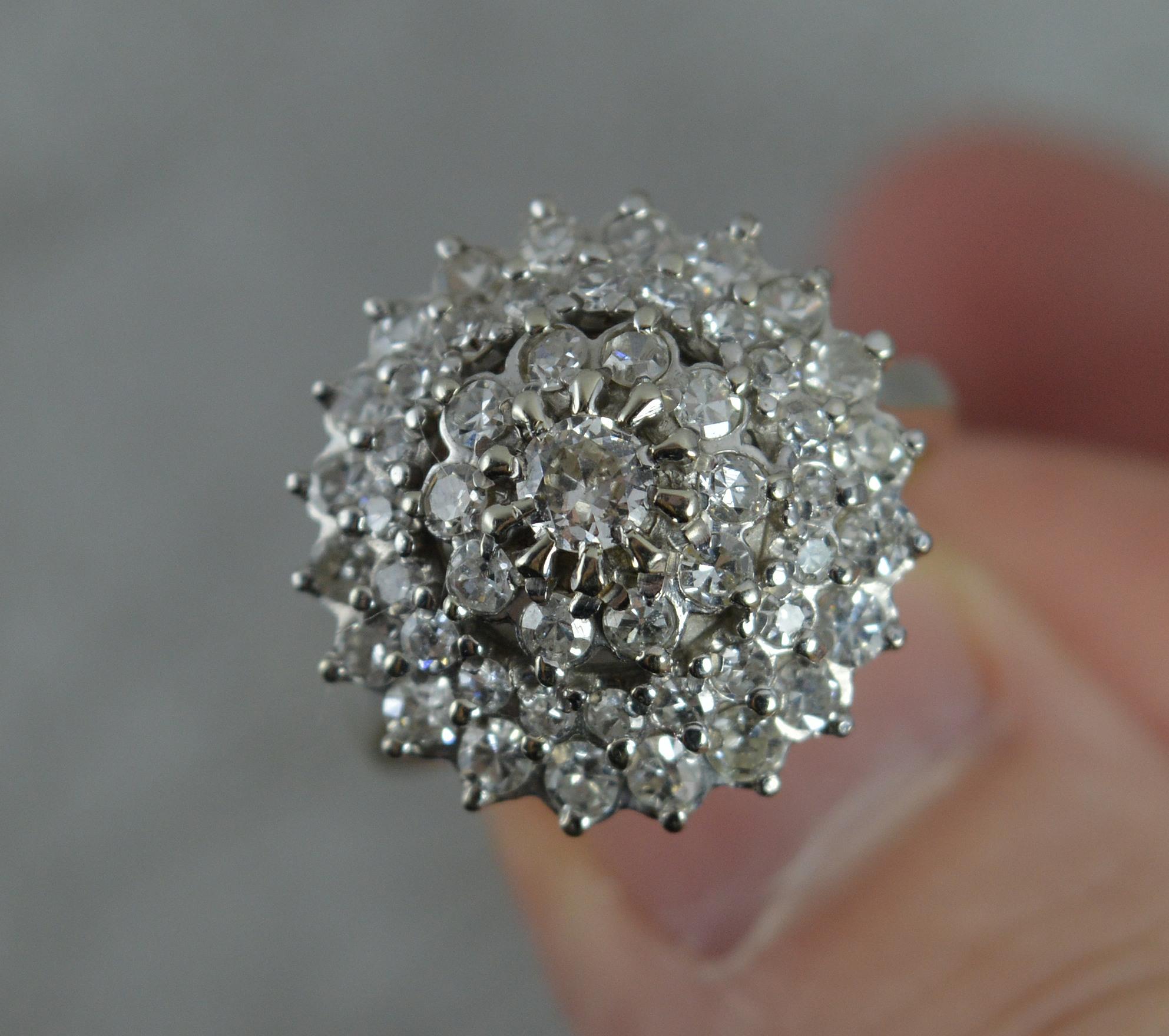 An impressive sparkly 18ct gold and diamond cluster ring.
Solid 18 carat white gold example.
Set with many natural, round brilliant cut diamonds forming a four tier head.
17mm x 17mm cluster head. 1.4 carat total diamond weight. Clean and sparkly.