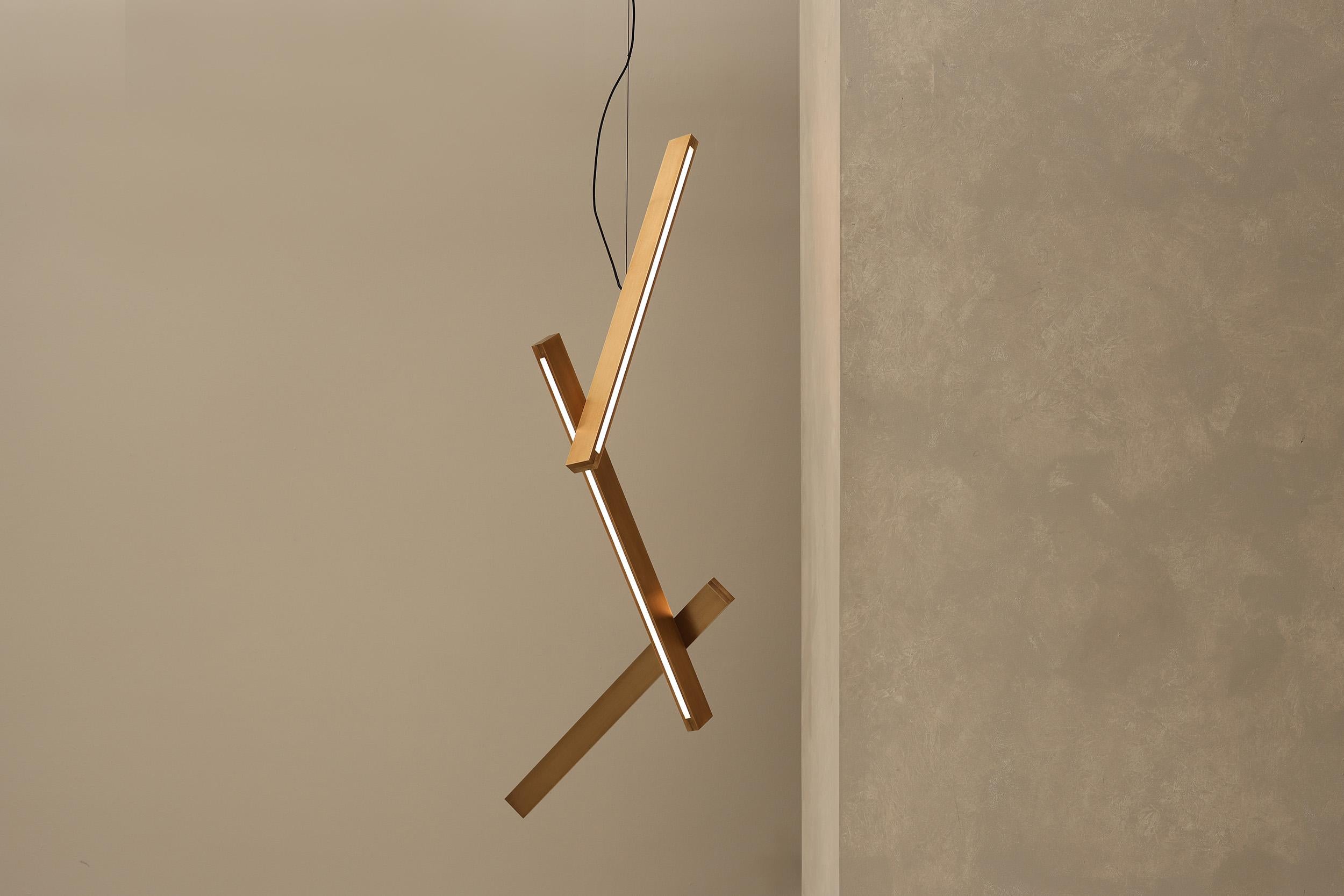 Avec des formes entrecroisées épurées et une finition en métal brossé, la suspension Bloc offre une présence architecturale raffinée. Le pendentif est fabriqué à partir de blocs de laiton ou d'aluminium usinés avec précision. Sa puissante LED