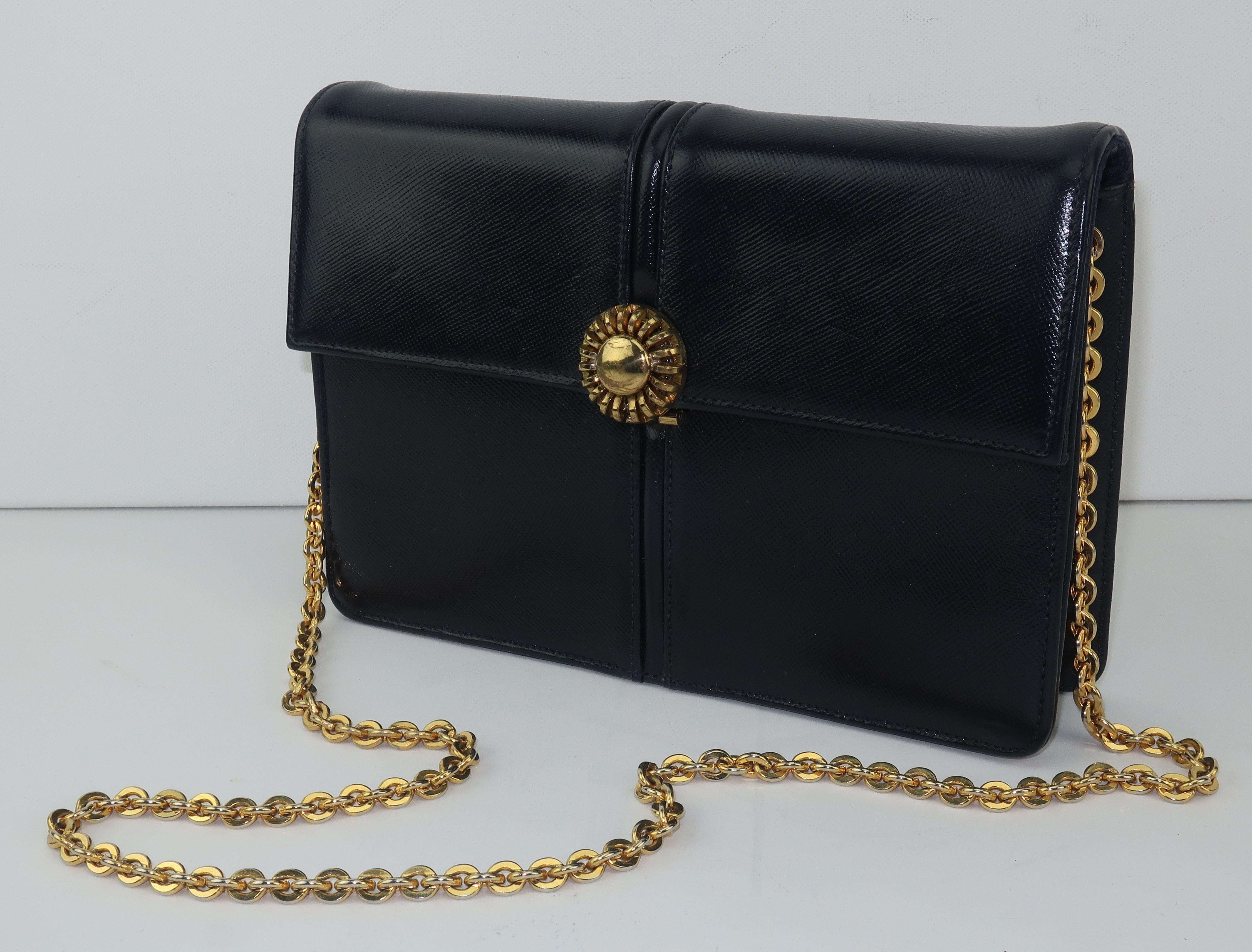 A period perfect 1960's ladylike black leather handbag by Block with sunburst style closure and chunky chain shoulder strap.  The sunburst closure hinges open to reveal a grosgrain fabric lined interior with one open pocket and a zippered