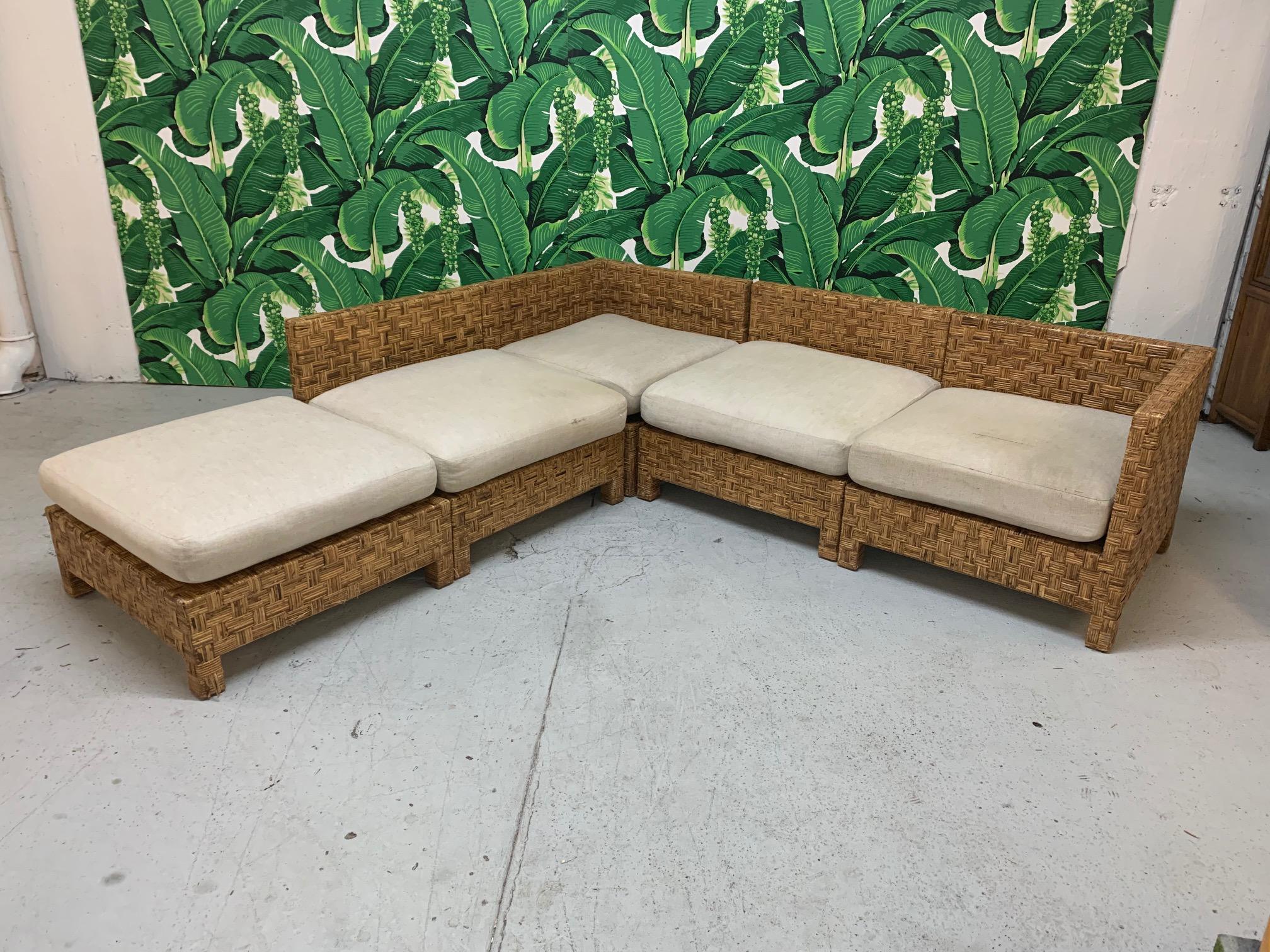 5-piece sectional sofa features woven block wicker design and modular pieces that can be arranged in several configurations. Design in the manner of John Hutton. Consists of 2 corner pieces, 2 side pieces, and an ottoman piece. Good vintage