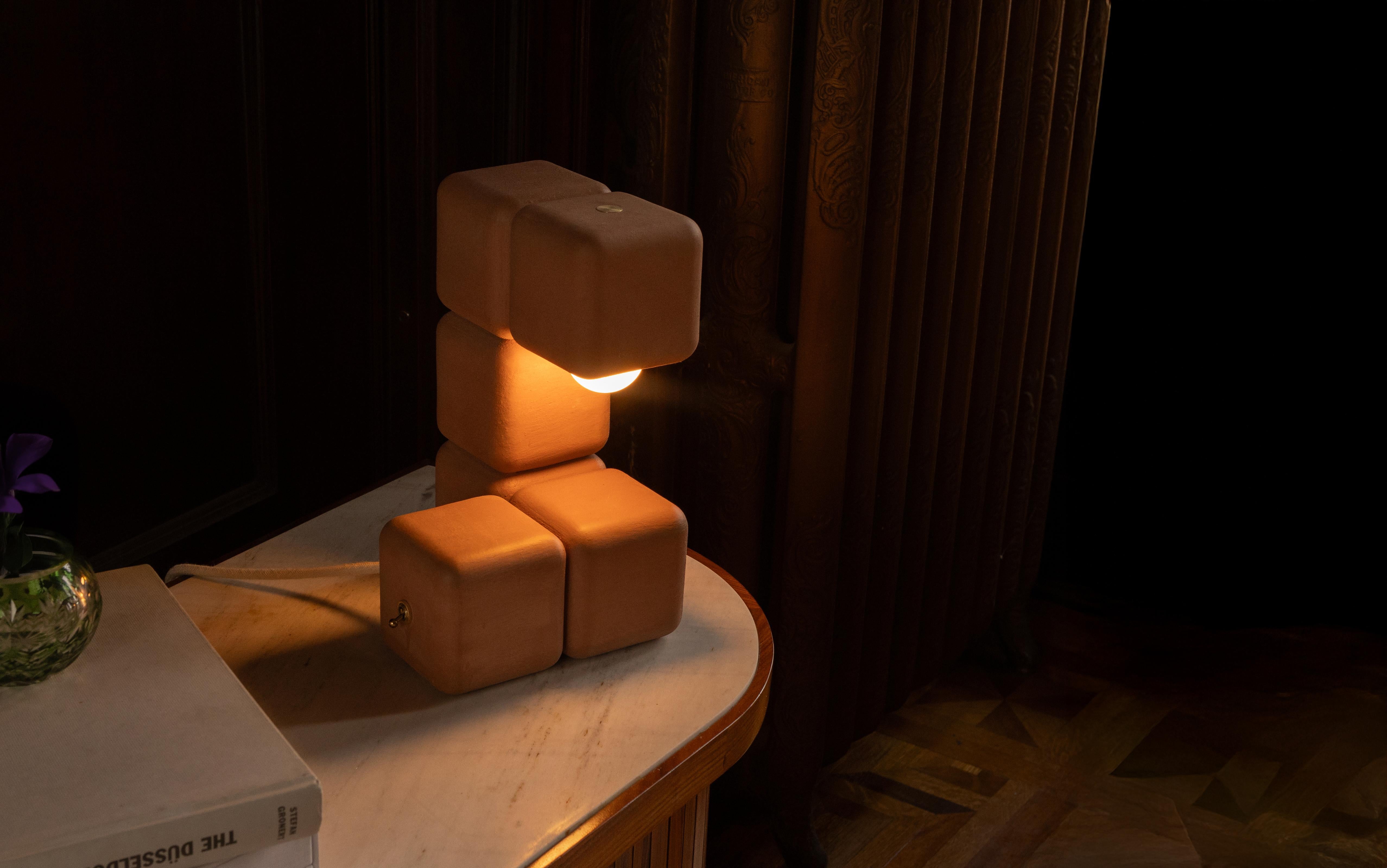 La lampada da tavolo Blocky porta un'energia giocosa sul piano del tavolo e distilla la struttura in forme minimali: cubi impilati con bordi ammorbiditi, disposti ritmicamente. Spuntando dal cubo finale, la lampadina proietta una calda cascata di