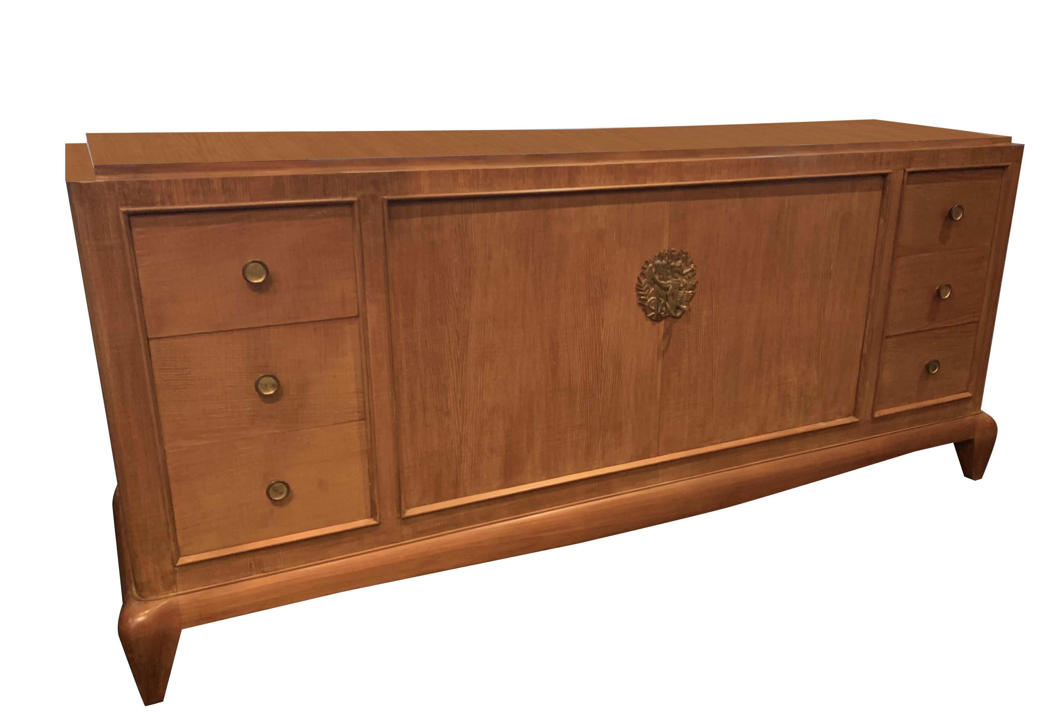 1940's French credenza designed by Jules Leleu.
Two front doors with signature bronze escutcheon depicting Adam and Eve at key closure.
Two sets of three drawers, on either end of credenza.
Blonde ash wood.
Recently restored.
Top width is