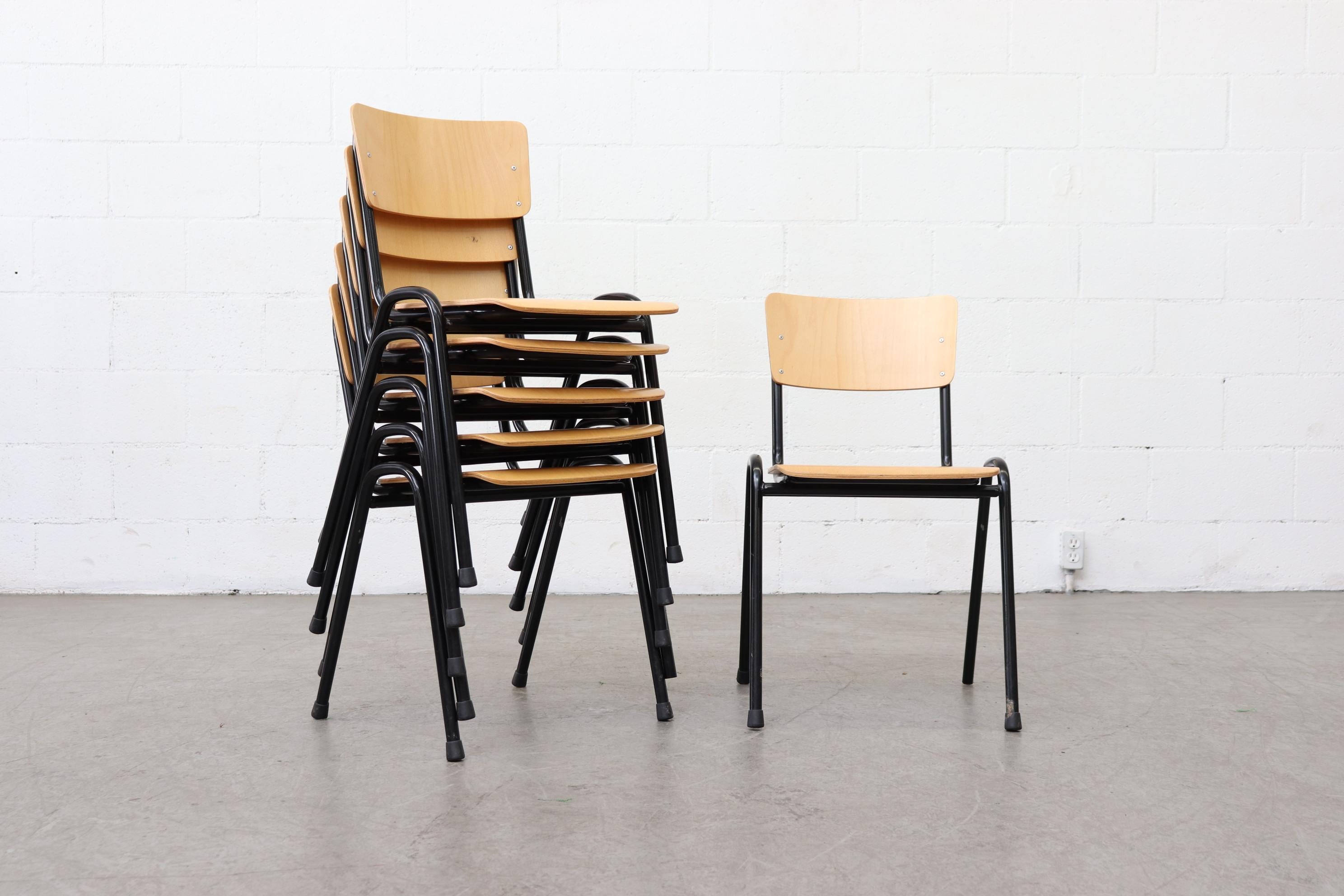 Blonde plywood industrial stacking chairs with black enameled metal tubular frame. In original condition with visible signs of wear including minimal chipping, scratching and enamel loss. All wear is consistent with their age and use. Priced