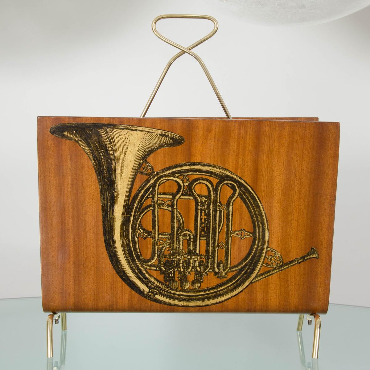 Blonde wood curved magazine rack with musical instrument design and brass details.