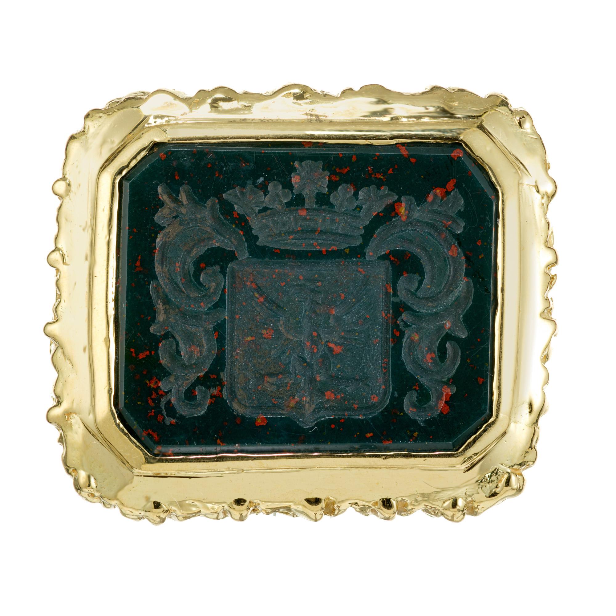 Large bloodstone gold ring. Octagonal natural untreated rectangle bezel encased bloodstone with a carved crest with an eagle in the center. We do not have information on the origins of the crest. The large grooved 18k yellow bezel, sits a top of a