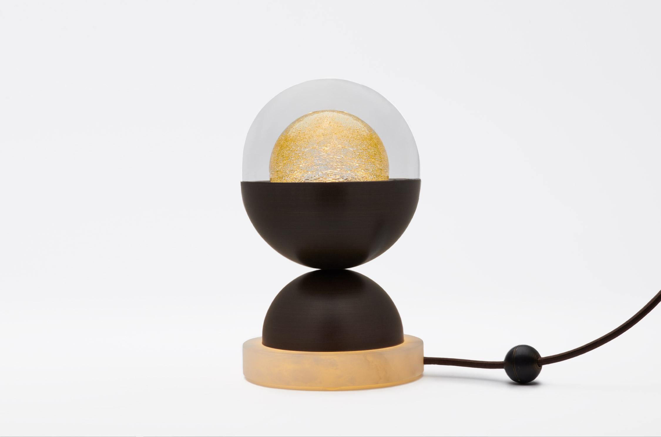 The Bloom table lamp's igenious design consists of glass, metal, and marble parts. The double glass orb (our Kadur pendant) rests inside a metal half-sphere, which is in turn balanced on another metal half-sphere attached to a round marble base. The