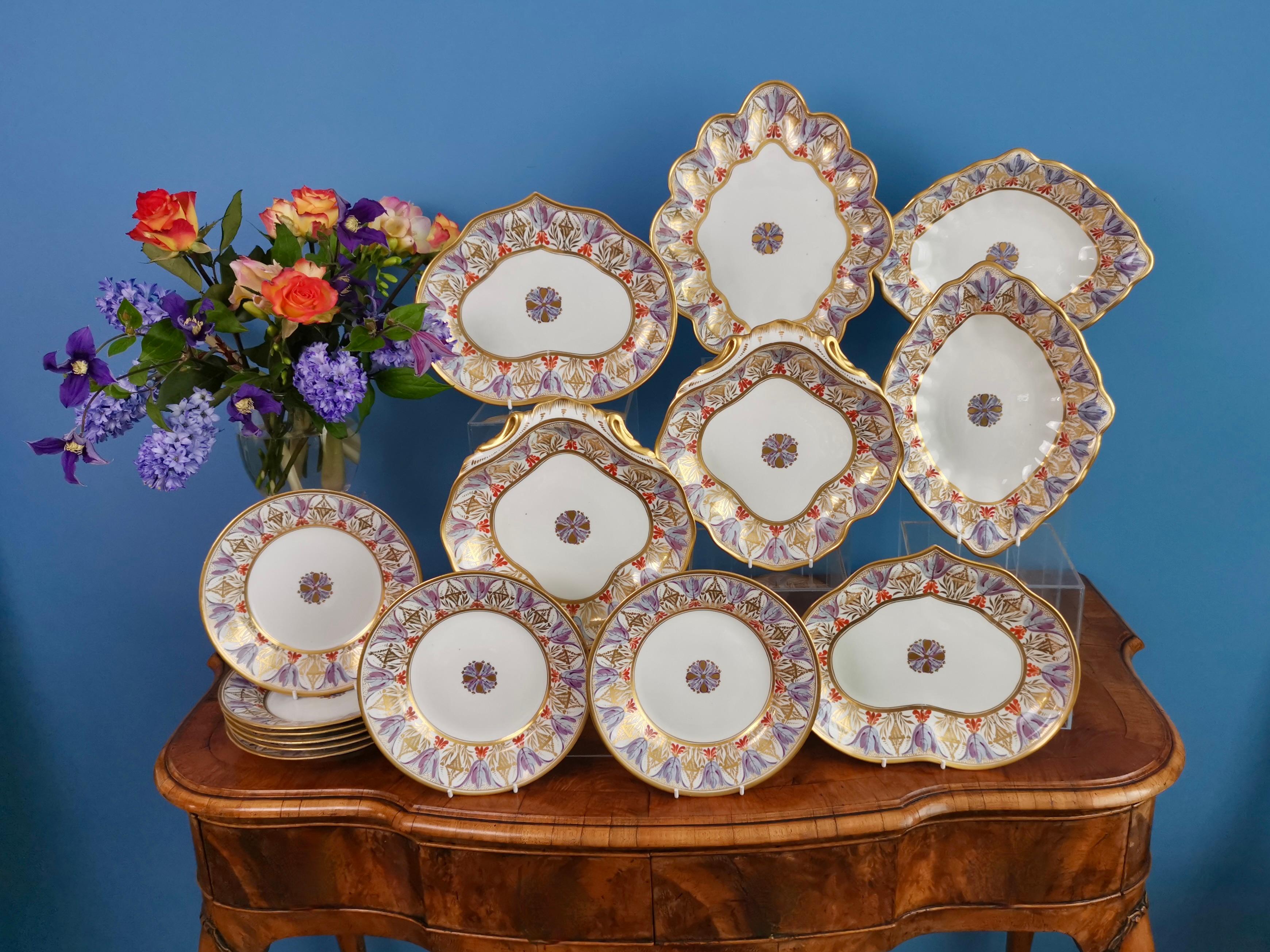 This is a stunning dessert service made by Derby between 1815 and 1820, which was the Regency era. The service consists of one large diamond shaped dish, two smaller diamond dishes, two kidney shaped dishes, two square shell dishes, and eight