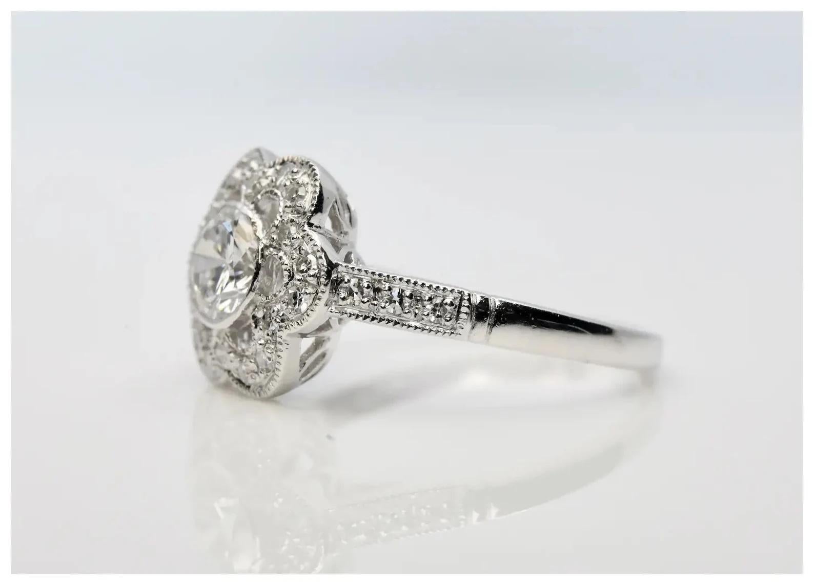 A chic floral motif diamond engagement ring in platinum.

Centered by a 0.55 carat round brilliant cut diamond of H color and VS1 clarity set in a polished platinum bezel.

Accented throughout in the petals of the flower and shoulders of the ring by