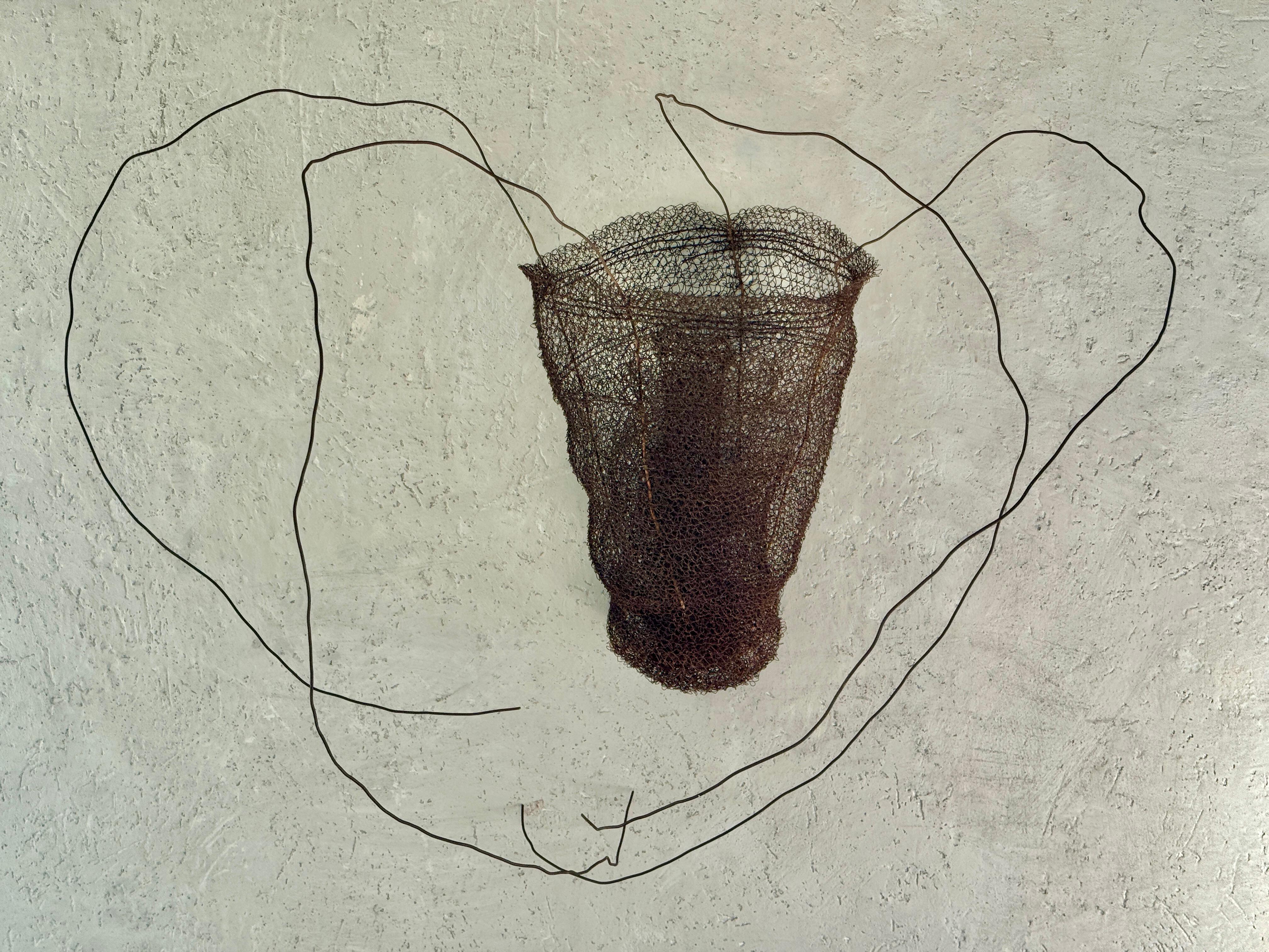 Una scultura delicata ed evocativa dell'artista contemporanea Lucy, intrecciata a mano con fili di metallo trovati, utilizzando tecniche di uncinetto e tessitura. L'opera, intitolata 