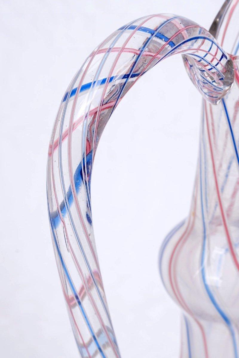 Belle aiguière en verre blanc de Murano, filigrane bleu et rouge, soufflée à la bouche.

Jusqu'aux XVIIe et XVIIIe siècles, les aiguières étaient utilisées pour servir les boissons.
Généralement en métal précieux or ou argent, finement sculpté et