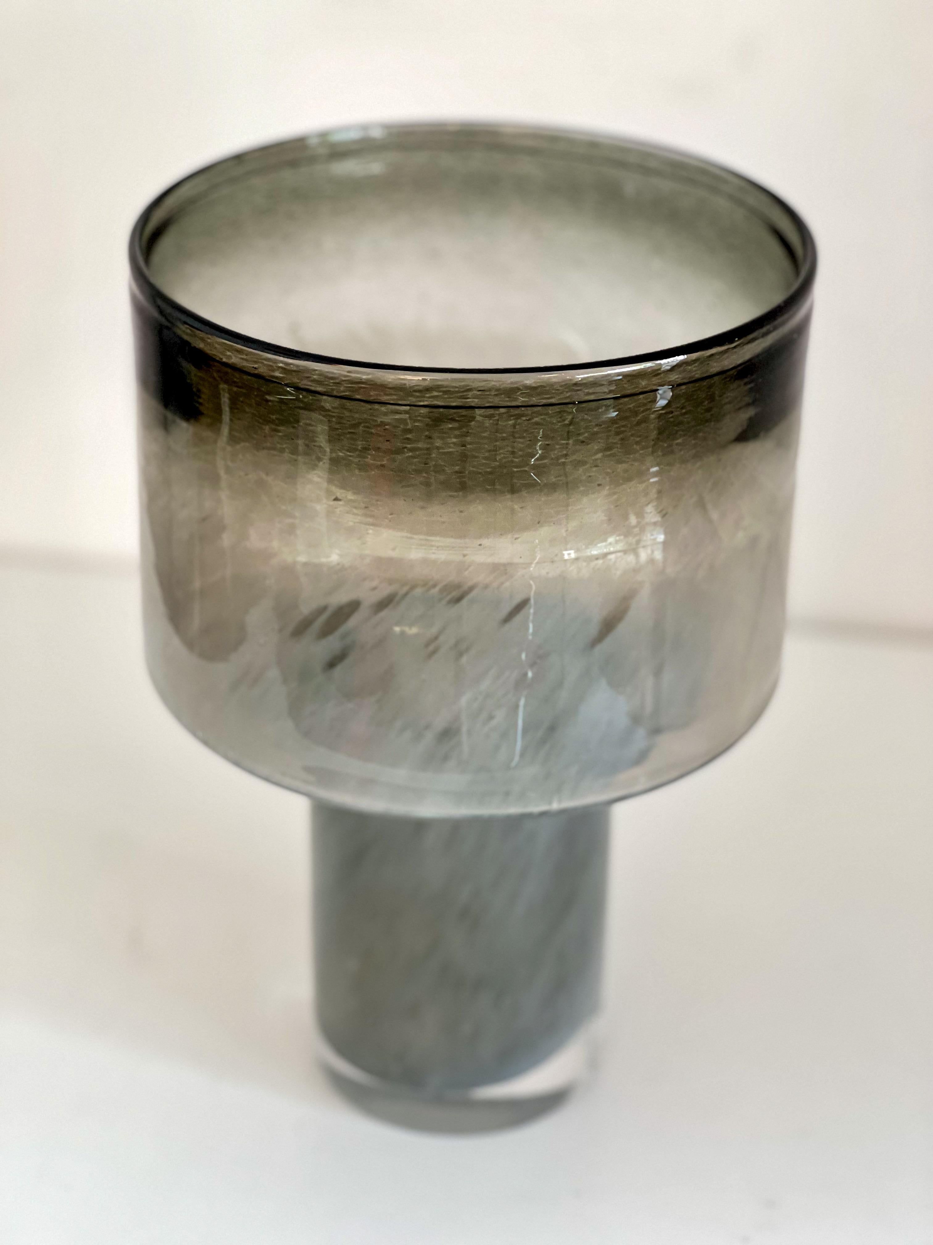 Chic cylinder vase 'on base' in beautiful smoked gray color.
Heavy glass
Graduation in colours - black, smoke, grey, white - all in one, creating a special effect. 
Semi transparent 
Designer, fabrication unknown 