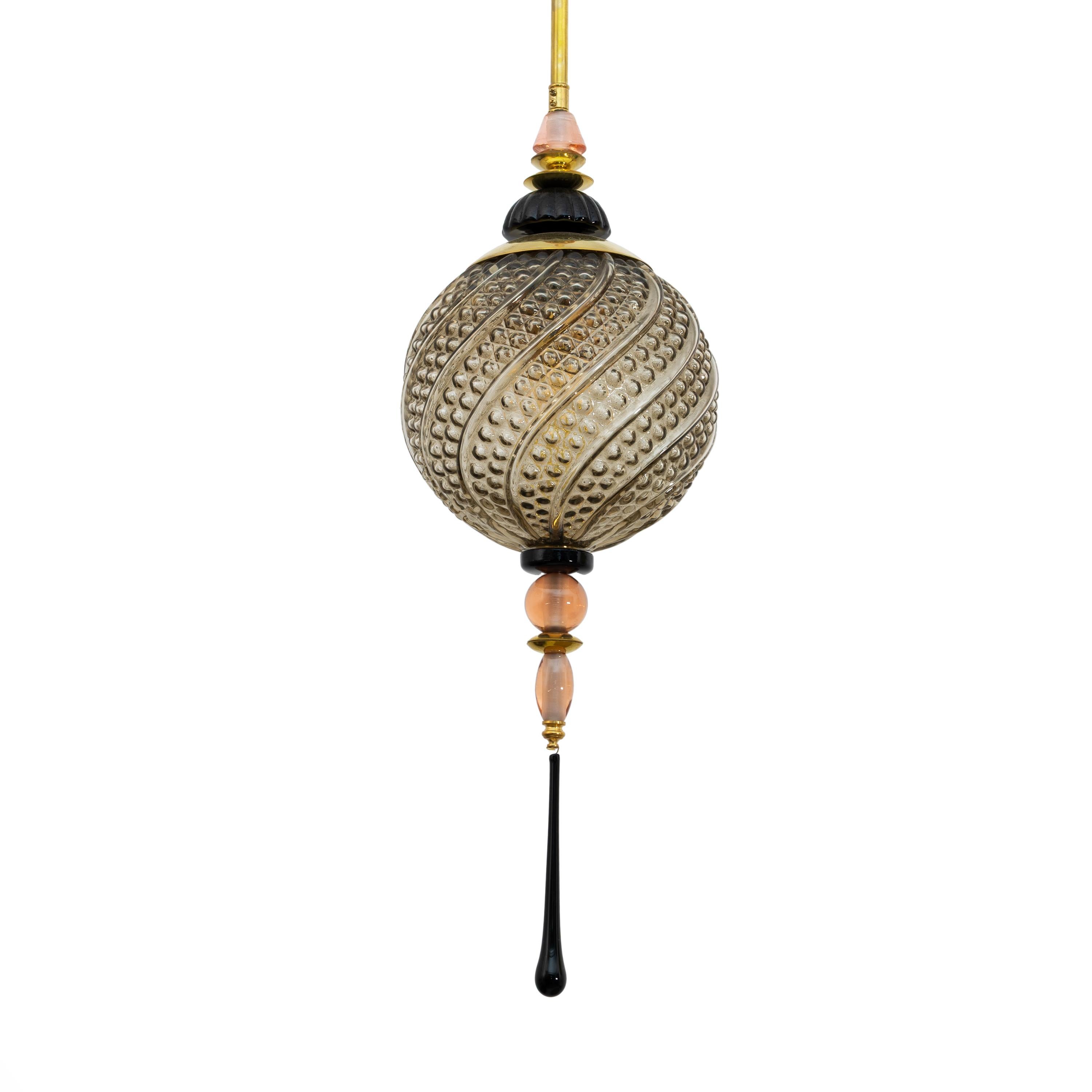 Un lampadario a lanterna in stile orientale contemporaneo, interamente realizzato a mano in Italia, qui presentato con elementi in ottone. La sfera rotonda organica è realizzata in un innovativo vetro di Murano soffiato a mano, affumicato e