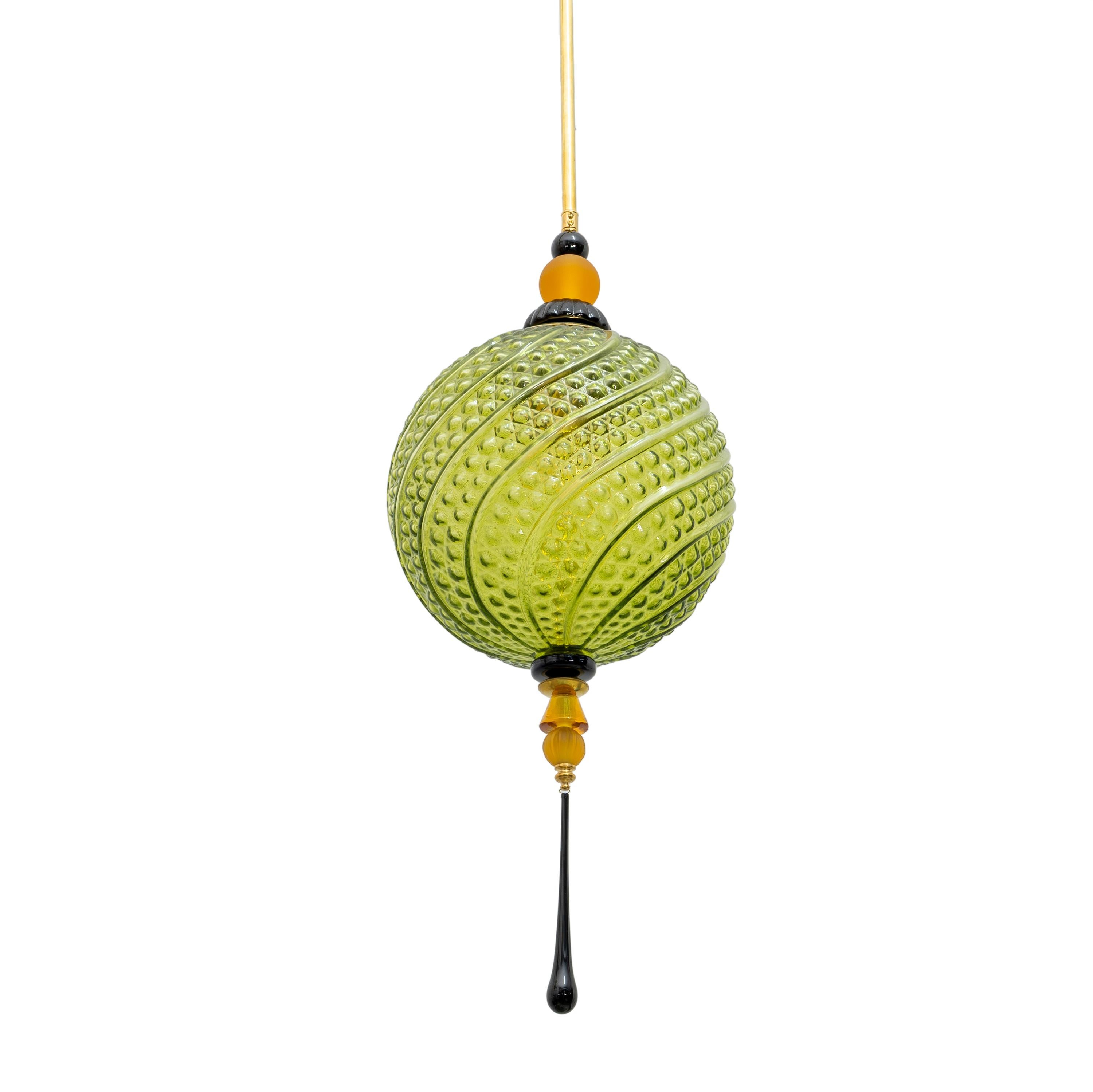 Un lampadario a lanterna in stile orientale contemporaneo, interamente realizzato a mano in Italia, qui presentato con elementi in ottone. La sfera ovale organica è realizzata in un innovativo vetro di Murano soffiato a mano, verde e strutturato con