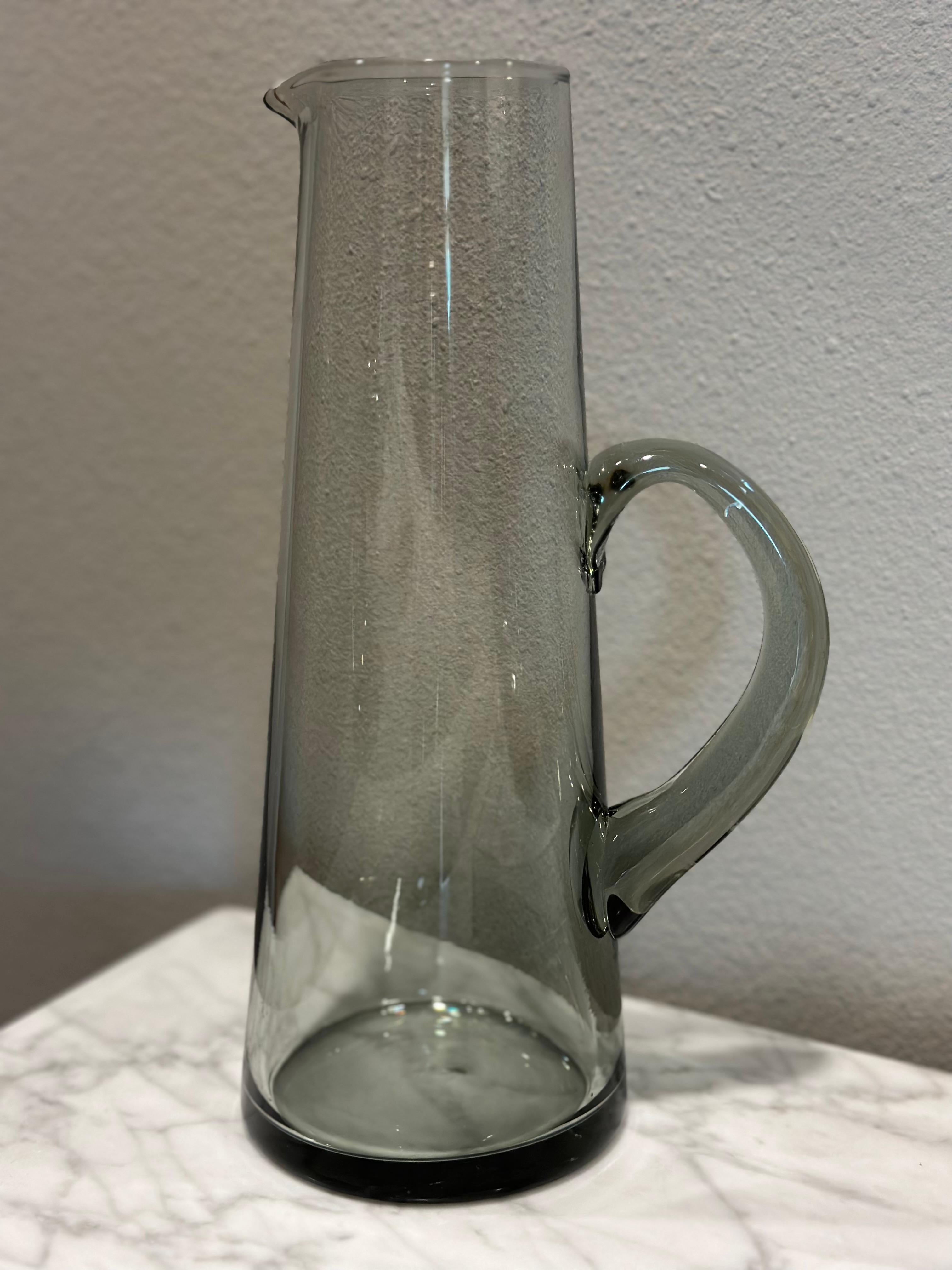 This late 20th century glass pitcher is an exemplary example of modern art. Handcrafted with intricate care out of smoke-hued glass, it is in pristine condition with no chips or any other kind of damages.