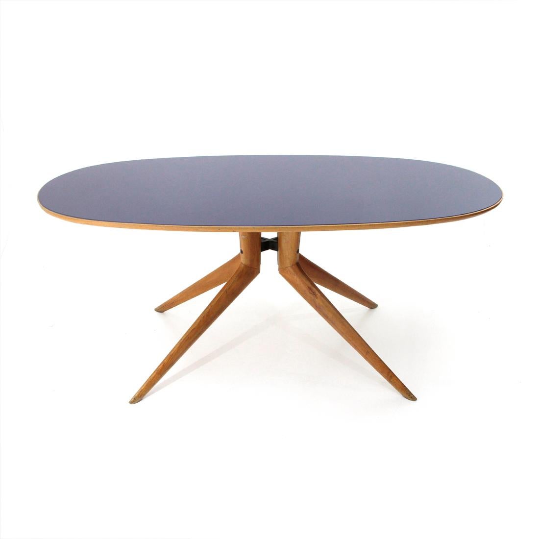 Italian manufacture table produced in the 1950s.
Oval wooden top with tapered edges with blue glass surface.
Central foot with black painted metal pin and shaped solid wood legs.
Good general conditions, some signs due to normal use over