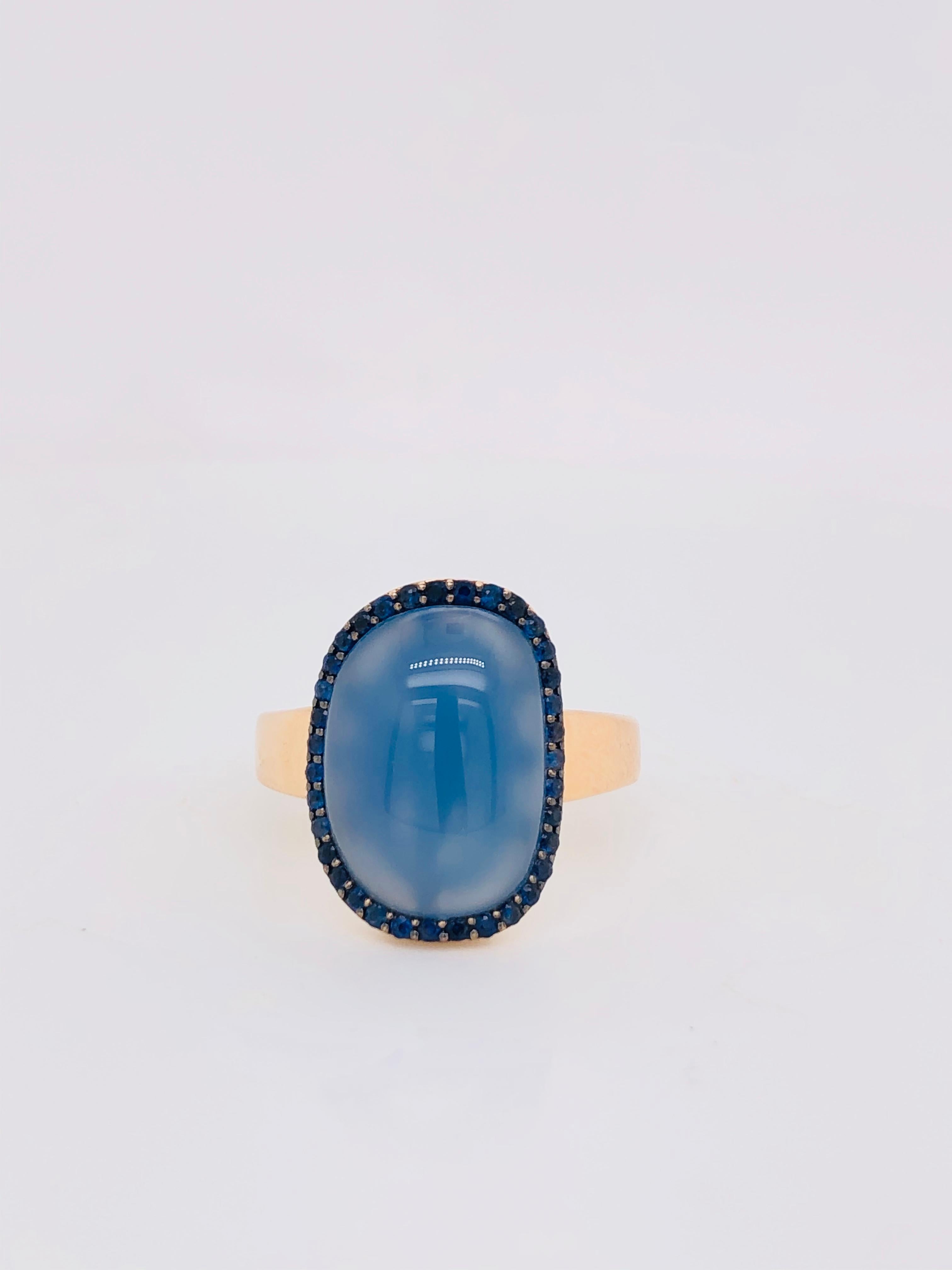 Discover this magnificent 18-carat rose gold ring, carefully crafted to bring timeless elegance to your jewellery collection. This exquisite ring has a unique design featuring a stunning cabochon of blue agate, surrounded by a sparkling halo of