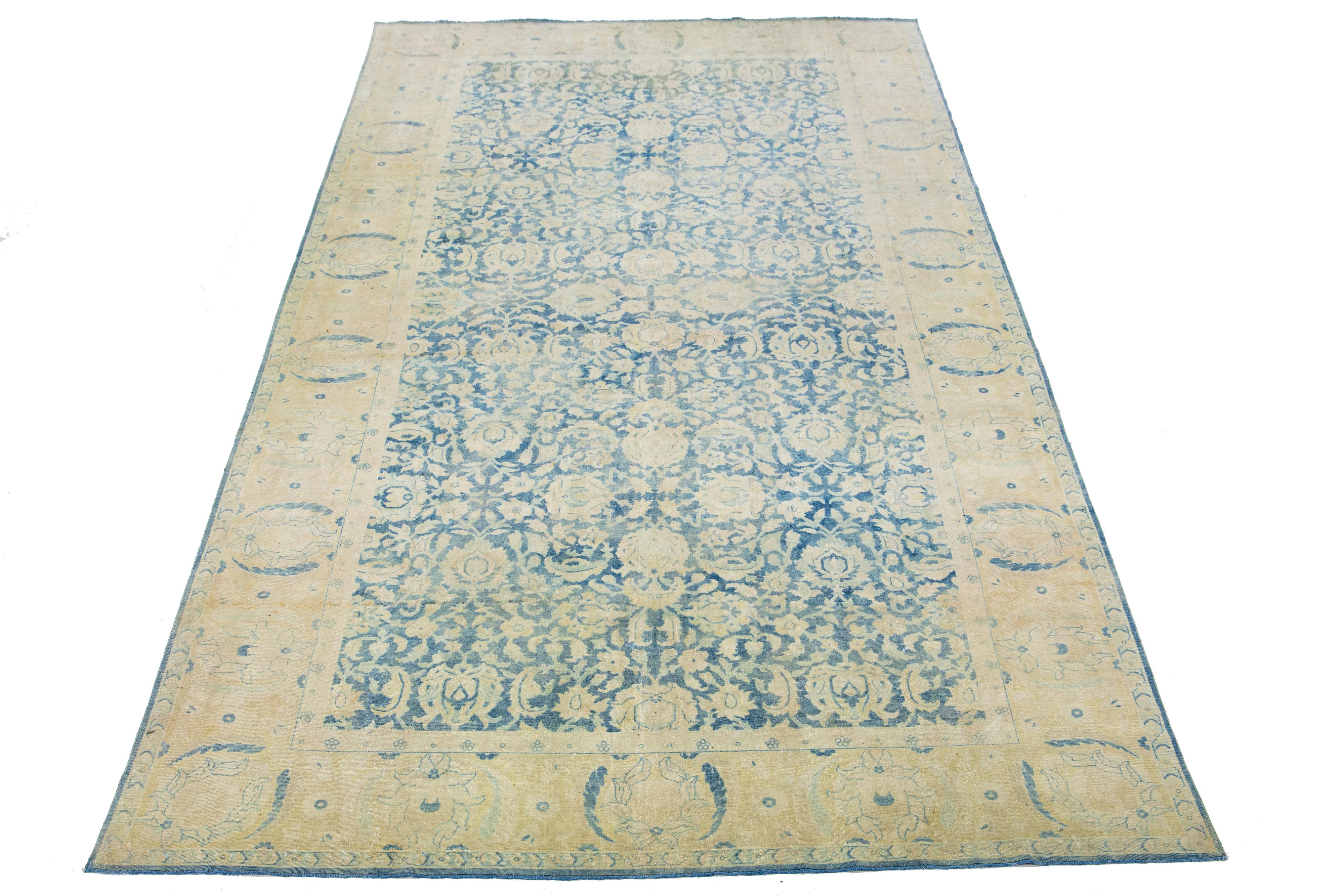 Beautiful hand-knotted antique Agra wool rug with a blue color field. This Indian rug has beige accent colors in an all-over floral design. 

This rug measures 8'8