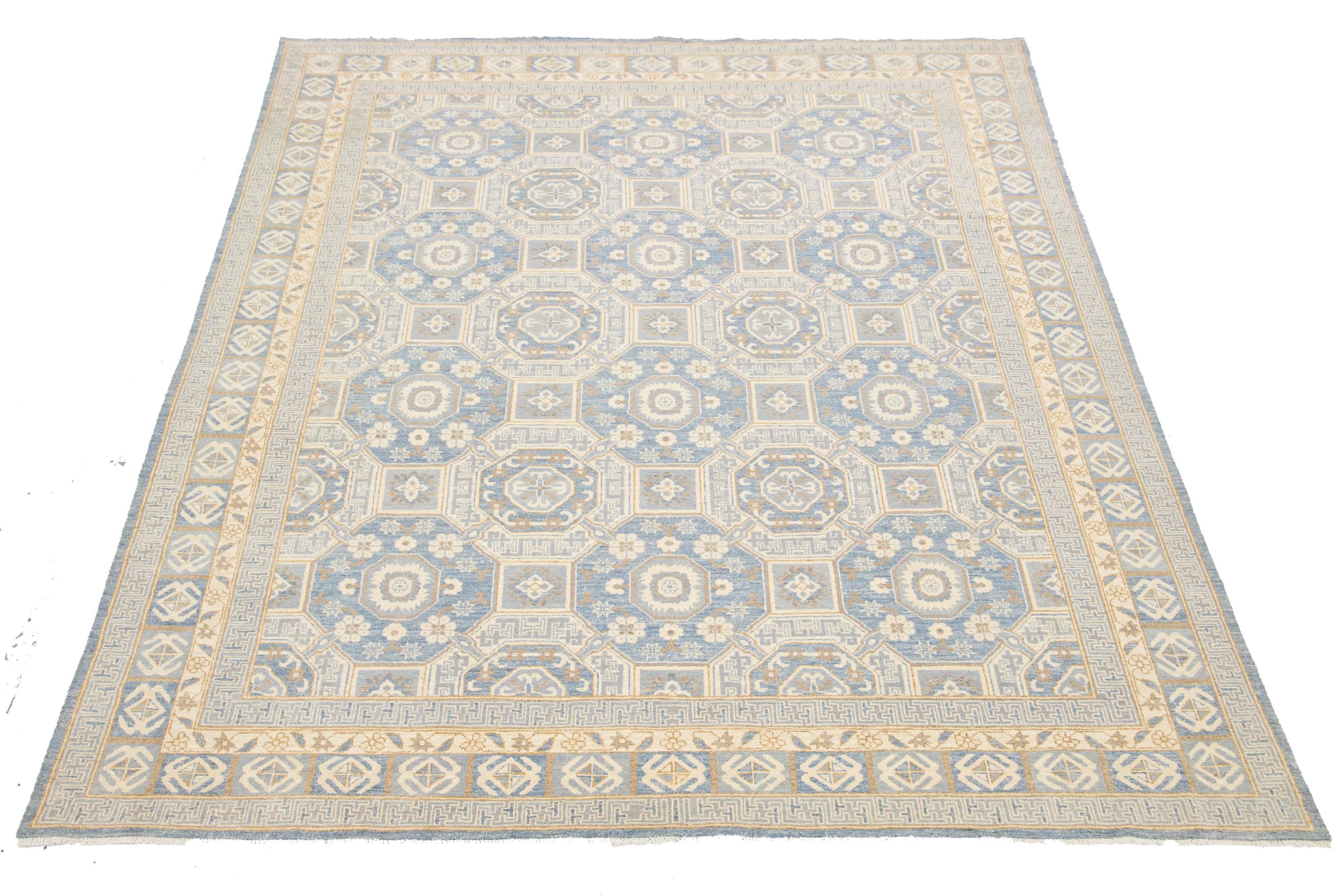 Ce tapis contemporain en laine de style Oushak met en valeur l'artisanat traditionnel. Il présente un fond bleu saisissant orné d'un motif géométrique complexe qui se mêle à des tons raffinés de beige, de gris et de verge d'or, ajoutant ainsi de la