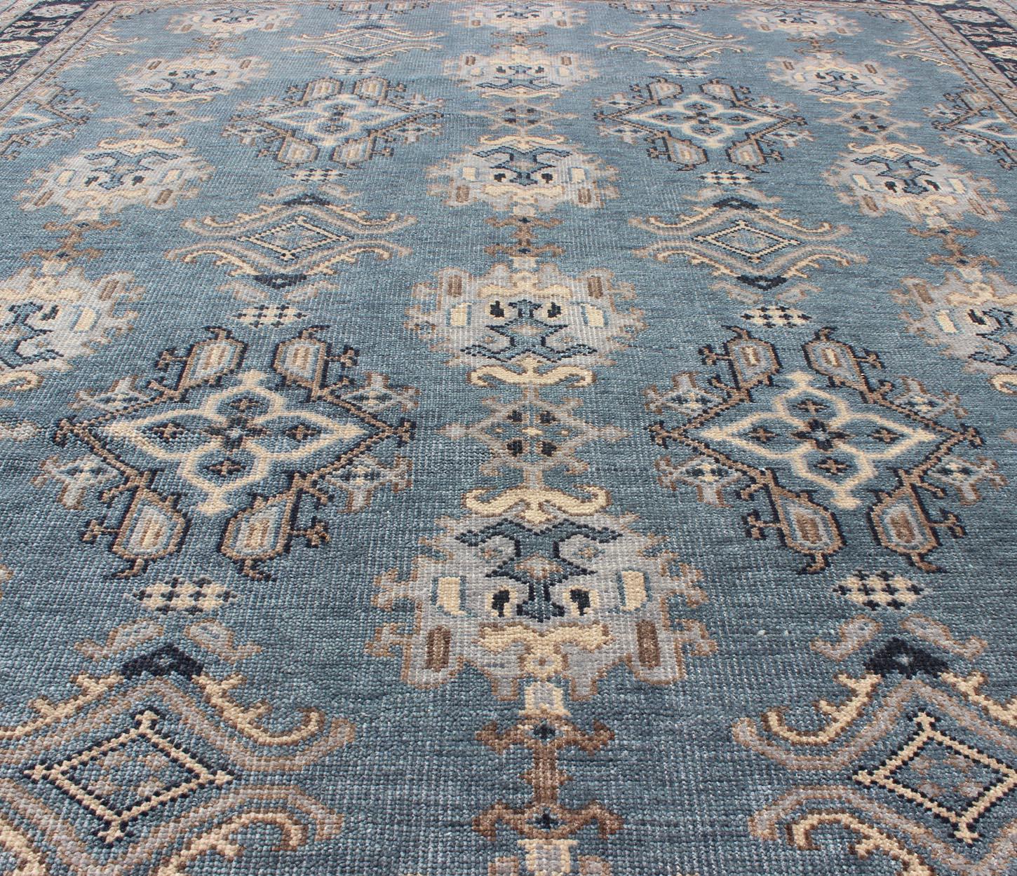 This uniquely designed Oushak, made by Keivan Woven Arts, was hand-knotted in India with wool and pile, resulting in a strong durability. The medium steel blue background displays a classic Oushak design with geometrics in light steel blue and