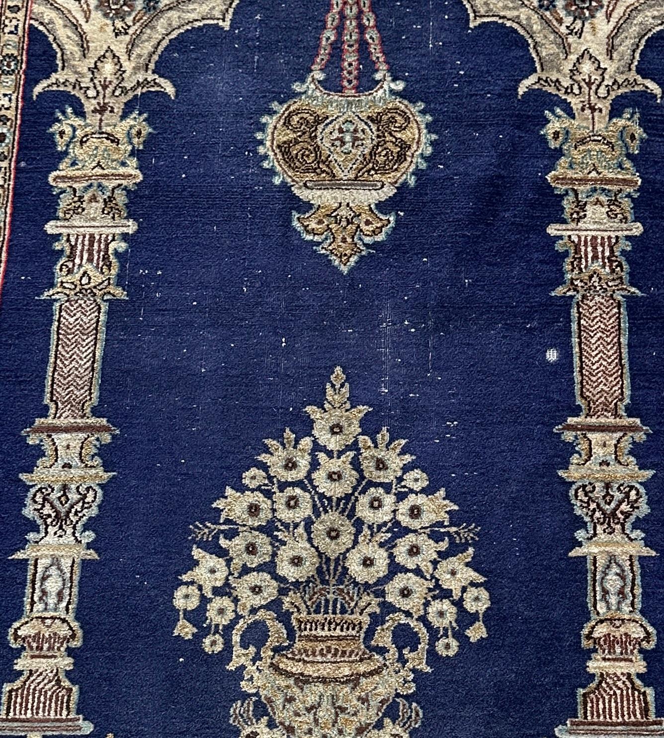 Enchant your living space with the exquisite beauty of our Blue and Cream Old Persian Accent Rug, adorned with a woven scene depicting flowers, pillars, and a chandelier. This rug is a masterpiece of Persian craftsmanship, showcasing intricate
