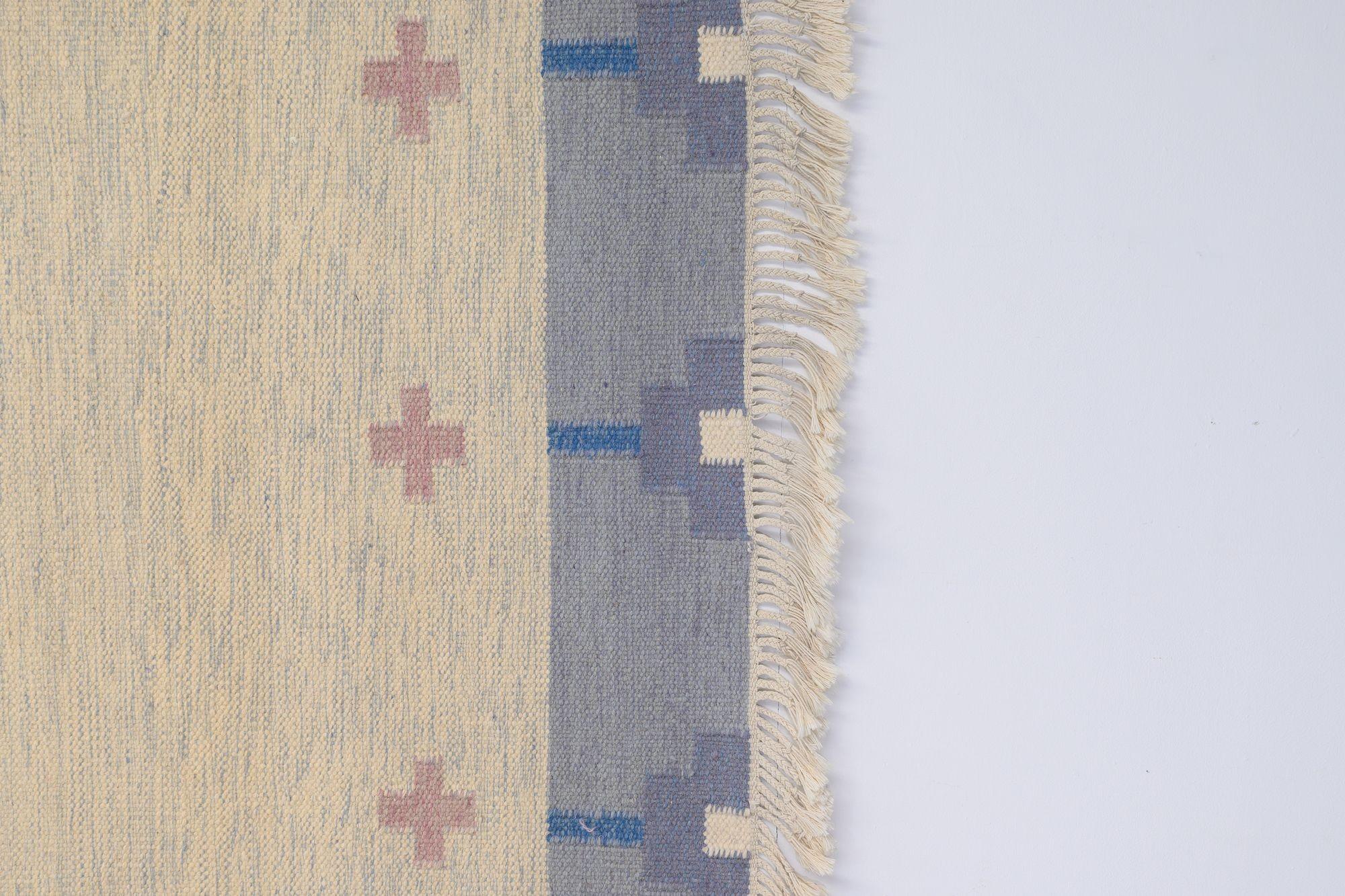 Kilim sueco de mediados de siglo con borde azul y campo crema. Decoración geométrica en forma de cruz rosa. Suecia hacia 1960. Todas nuestras alfombras se someten a un proceso de limpieza profesional. Sin embargo, debido a su antigüedad y vida