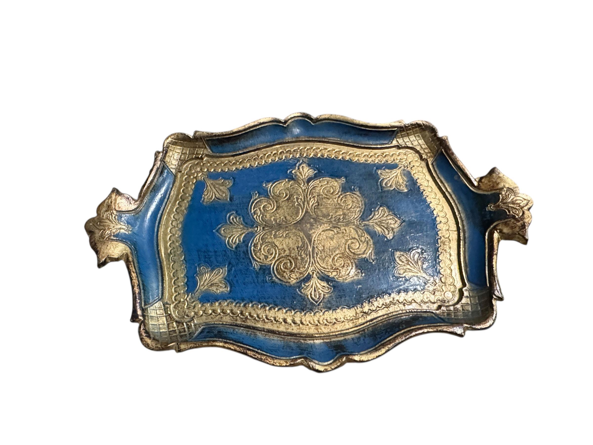 Un magnifique plateau Florentine peint à la main dans des tons de bleu et d'or saisissants. Cette pièce élégante reflète l'art classique de la dorure italienne, avec des détails ornementaux en relief et une patine douce, gagnée par le temps. Idéal